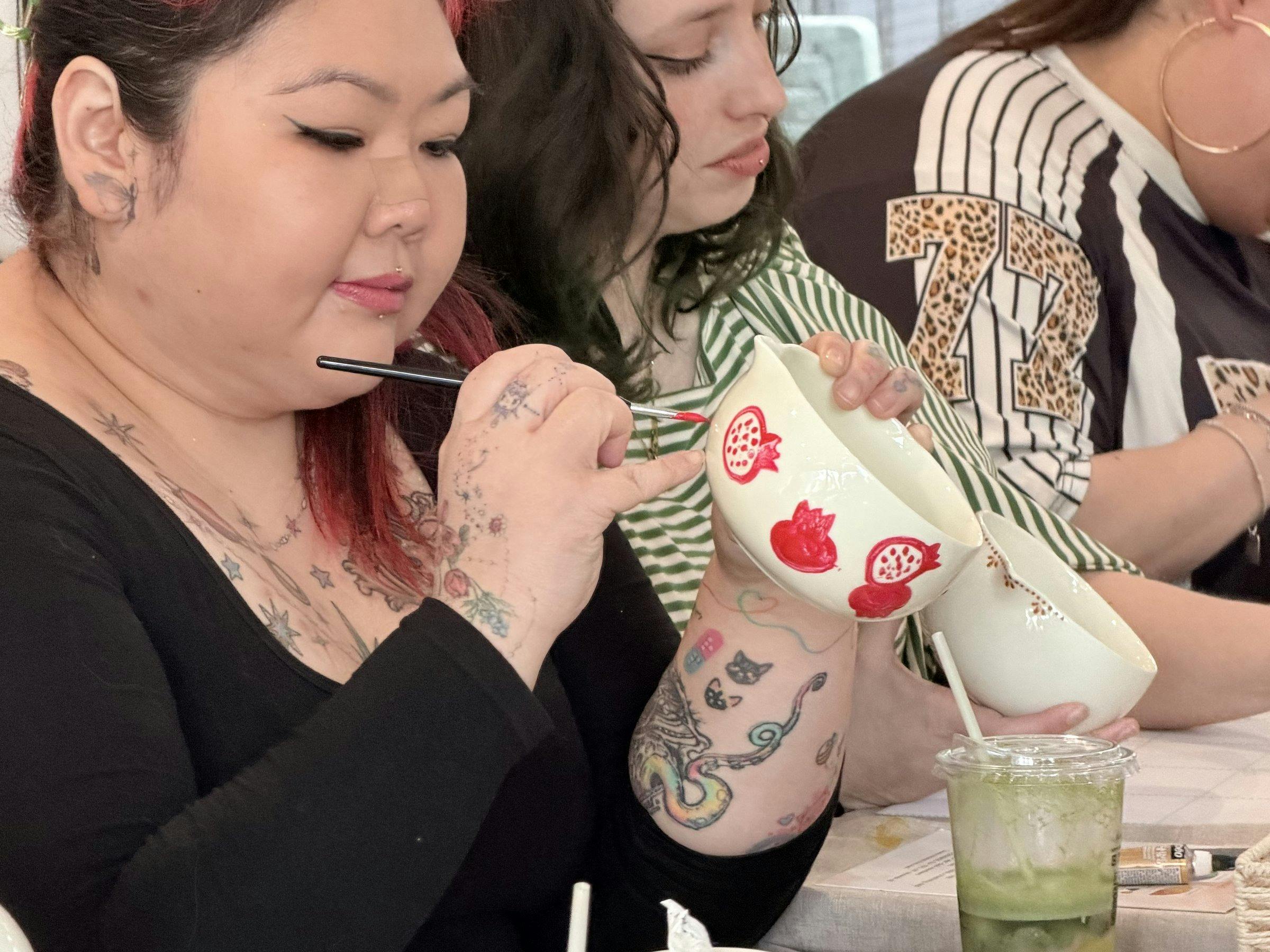 Guest hand-painting a ceramic cup at a NOA Matcha workshop