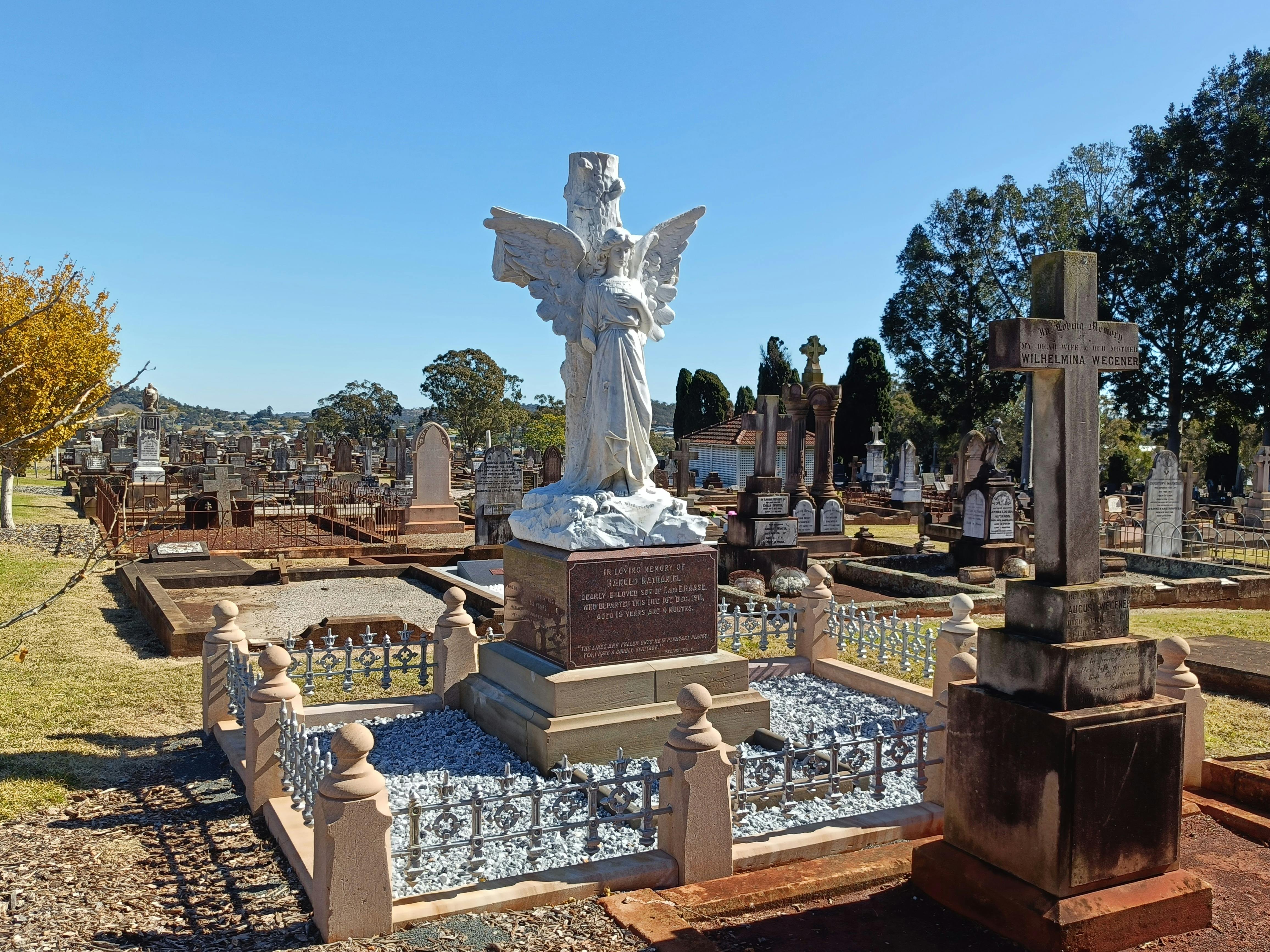 A large marble angel standing on a large base on a grave.