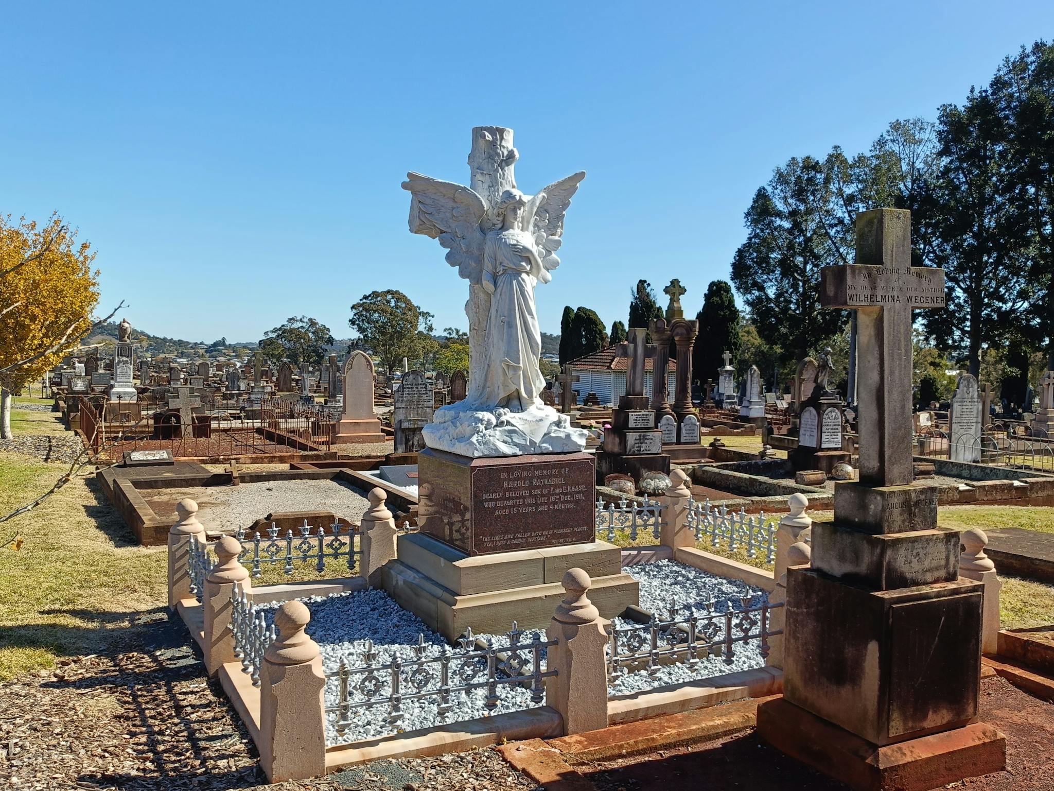 A large marble angel standing on a large base on a grave.
