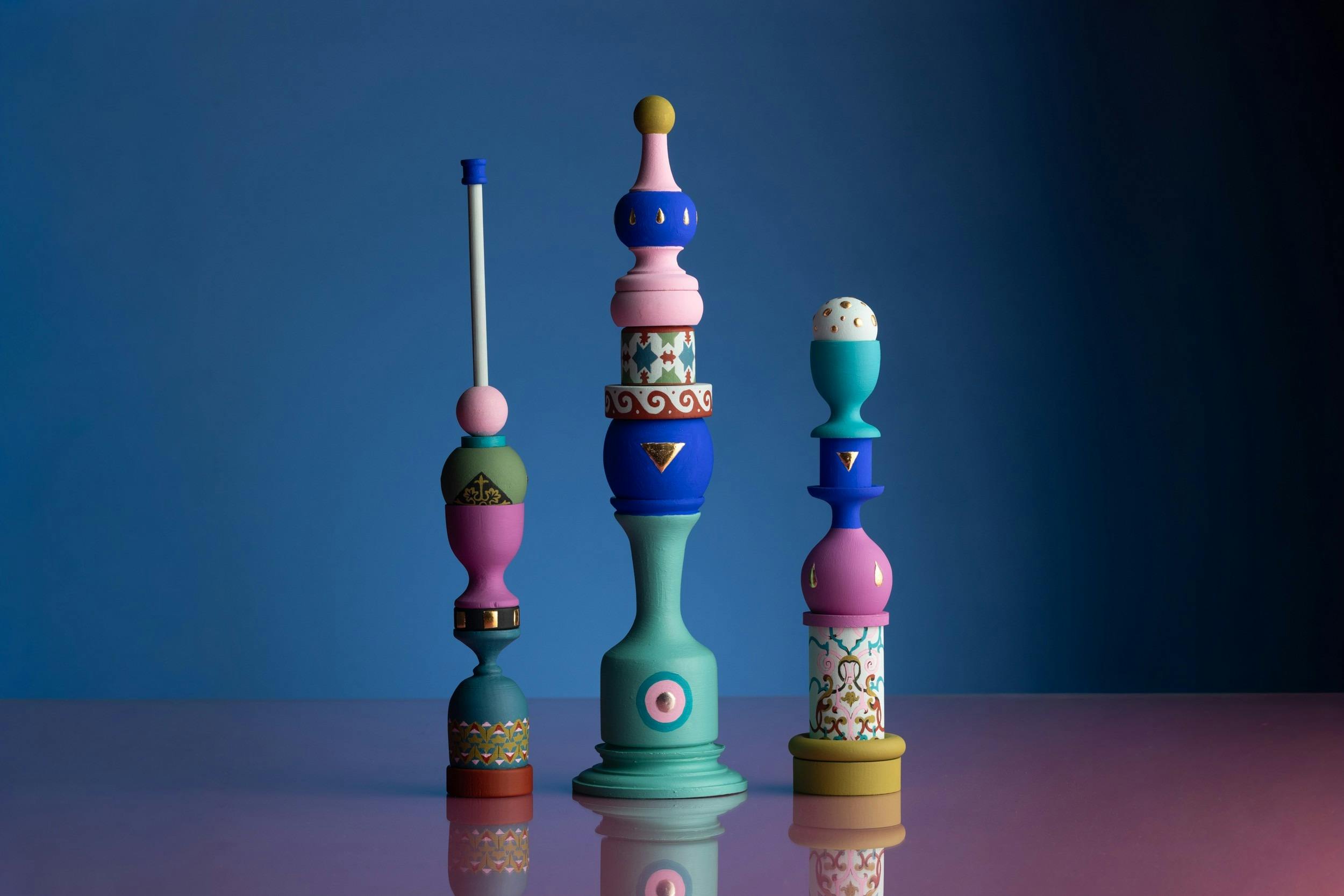 A photo of three colourful and sculptures made of objects piled on top of each other