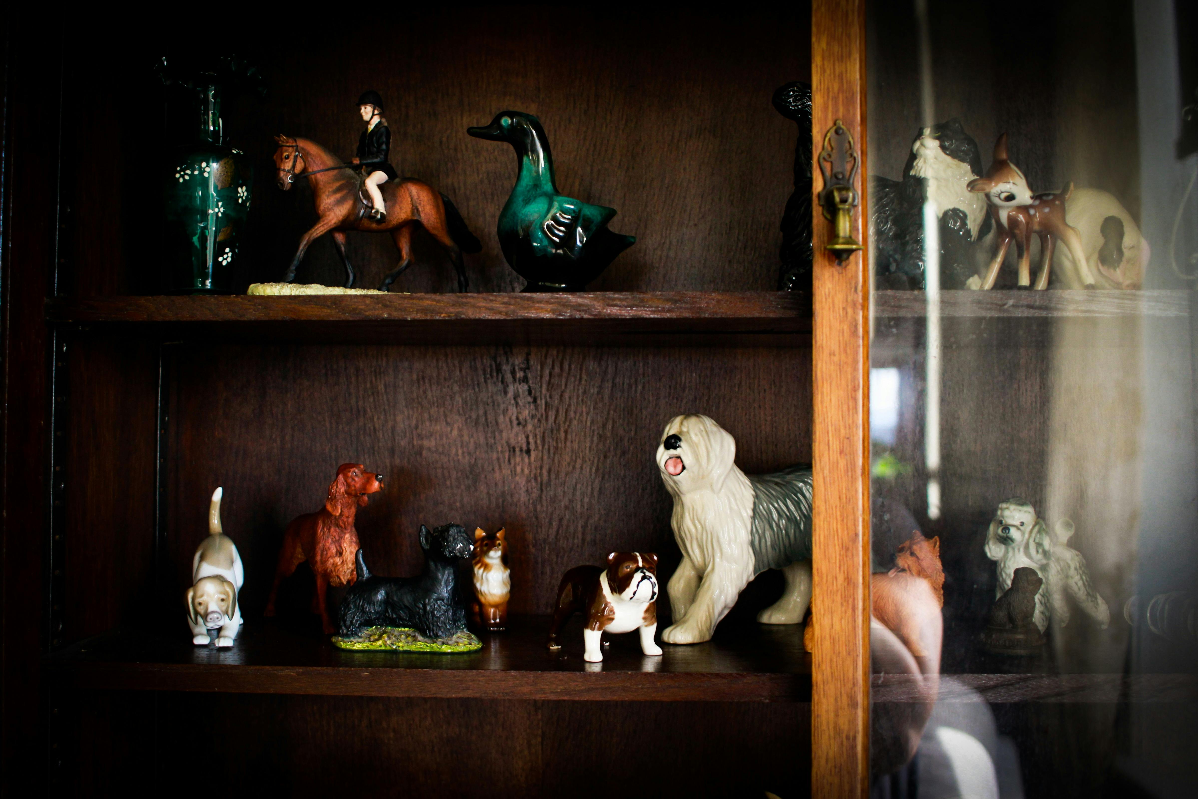 An antique cabinet filled with many Royal Doulton figurines