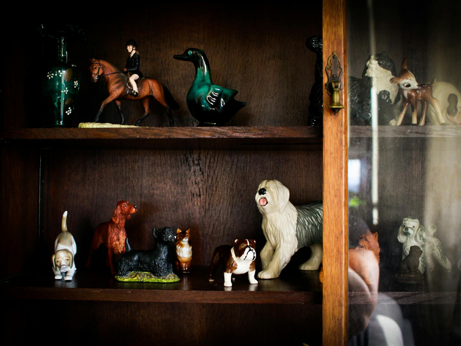 An antique cabinet filled with many Royal Doulton figurines