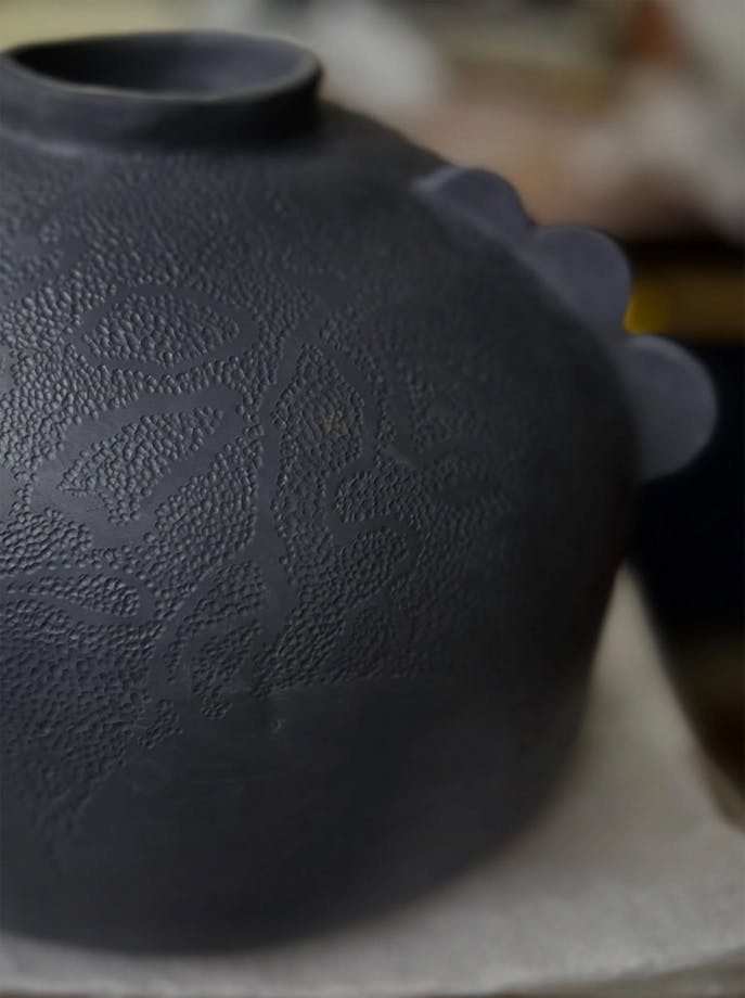 Dark round ceramic urn with dot texture