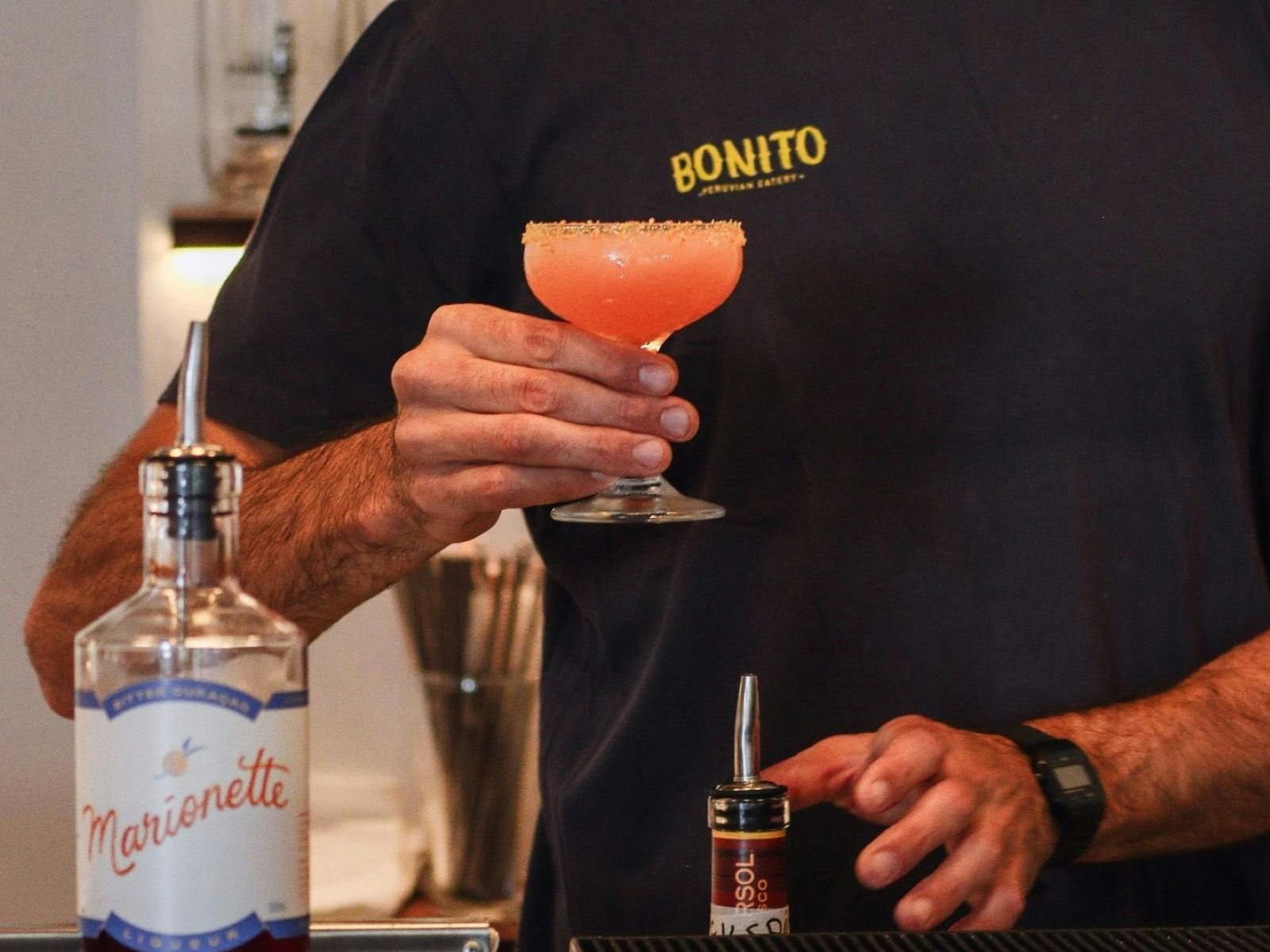 man making pink cocktail behind the bar