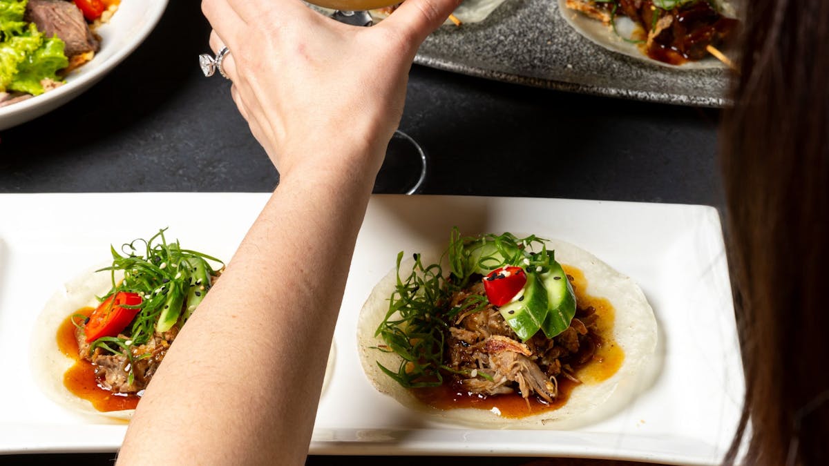 Asian fusion food spread with person holding cocktail