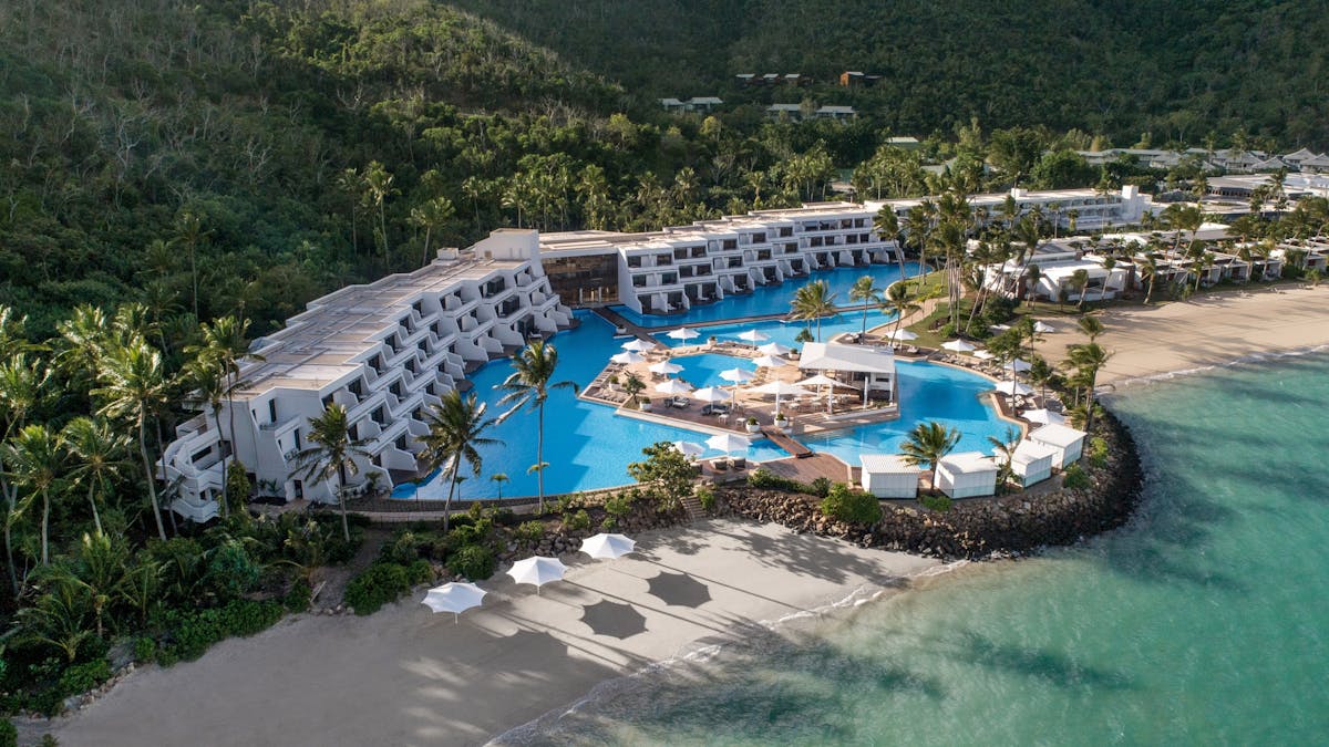 Aerial view of InterContinental Hayman Great Barrier Reef with a pool, white buildings, and a beach.