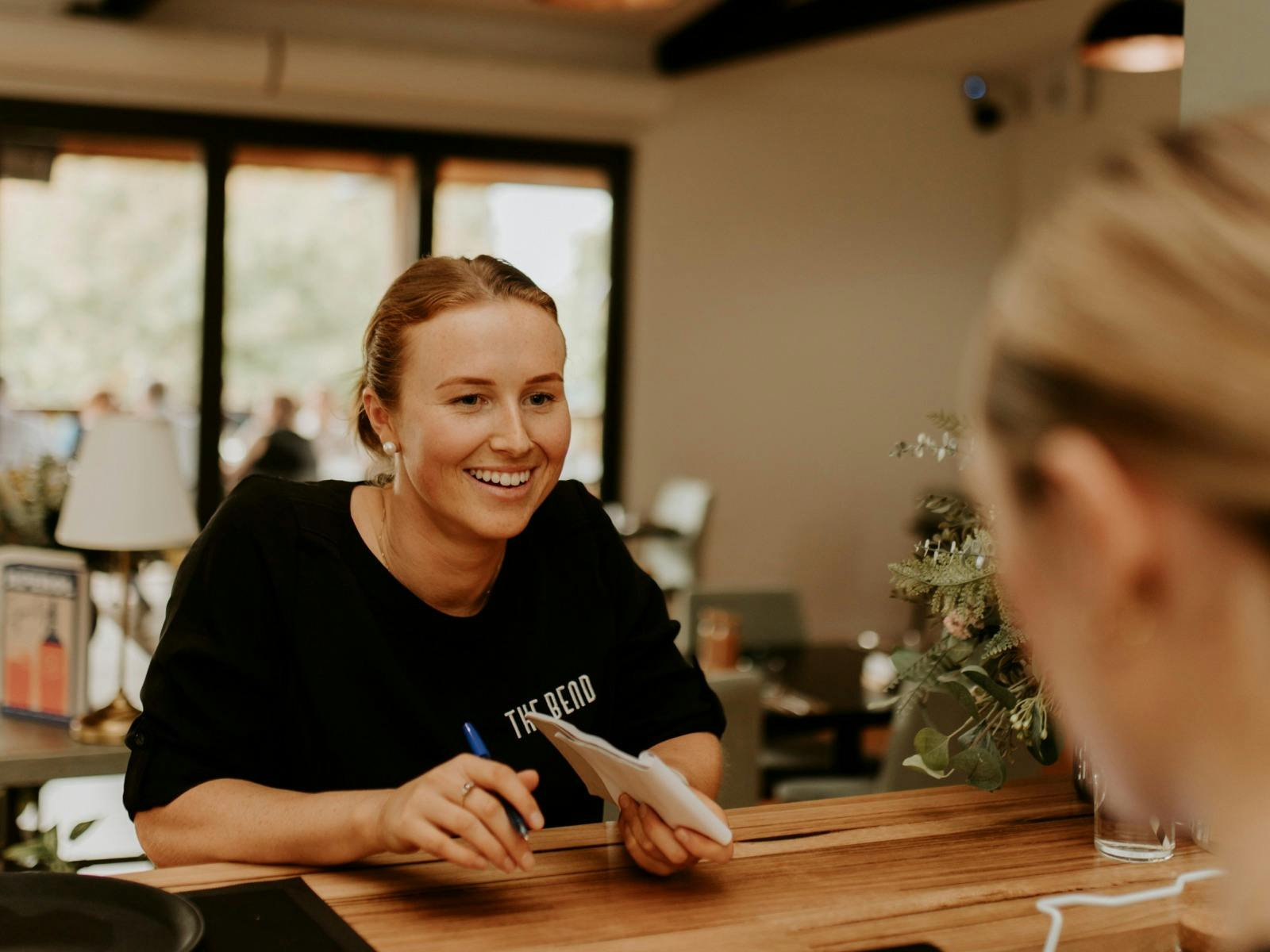 A staff member laughing and chatting over the bar at The Bend