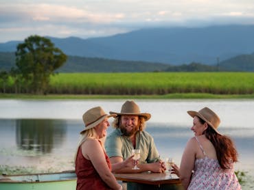 Three people enjoying a drink with the Oh Deere farm dam in the background Three people enjoying a drink with the Oh Deere farm dam in the background
