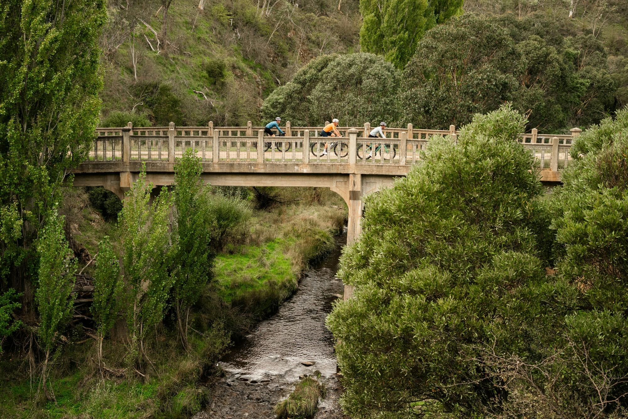 Three cyclists riding over a bridge on the Dinner Plain 7 Peaks Challenge route C