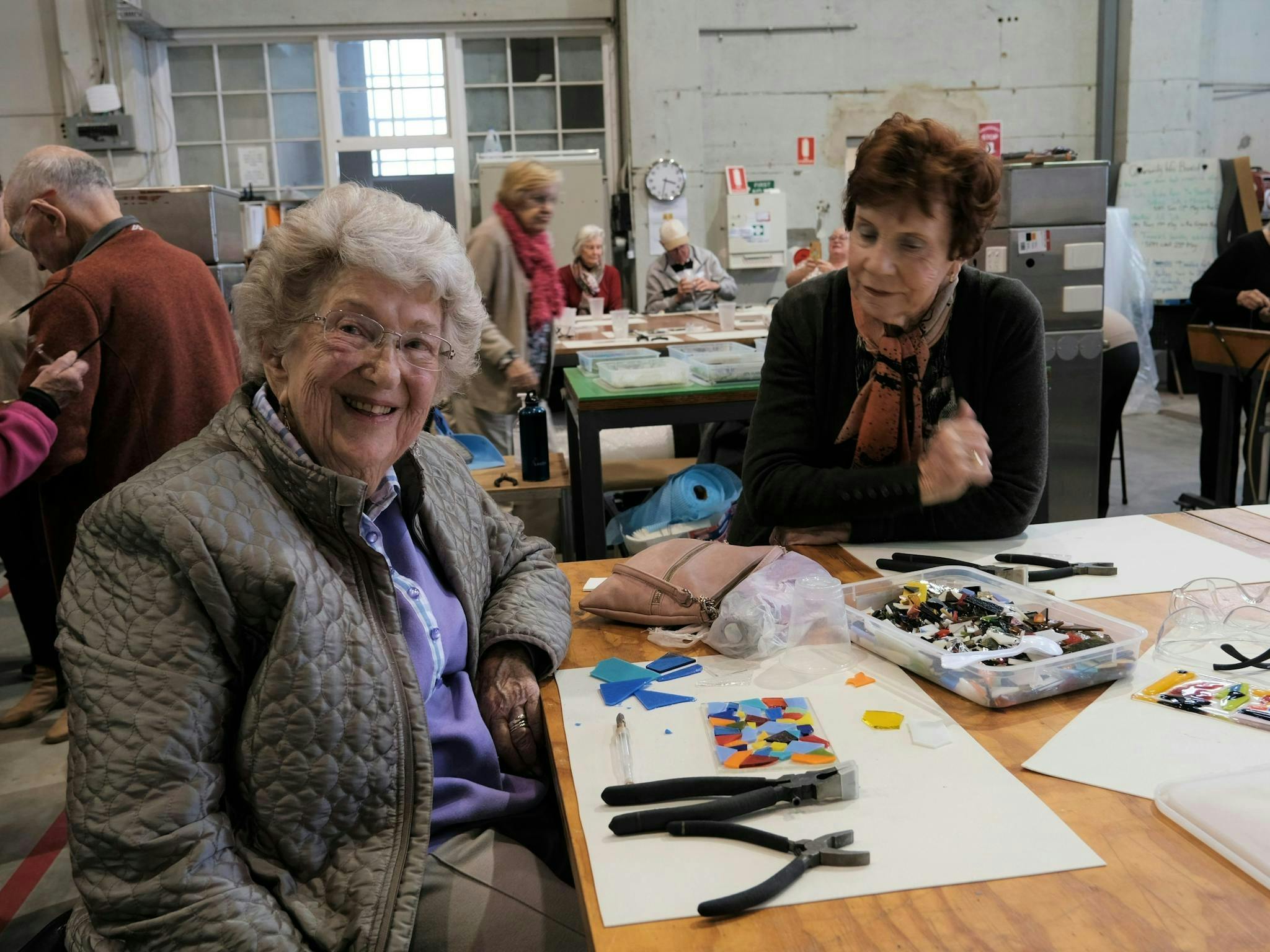 A glass mosaic tile making workshop in action, with two elderly ladys engaging