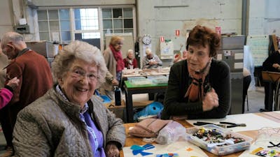 A glass mosaic tile making workshop in action, with two elderly ladys engaging