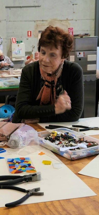 A glass mosaic tile making workshop in action, with two elderly ladys engaging