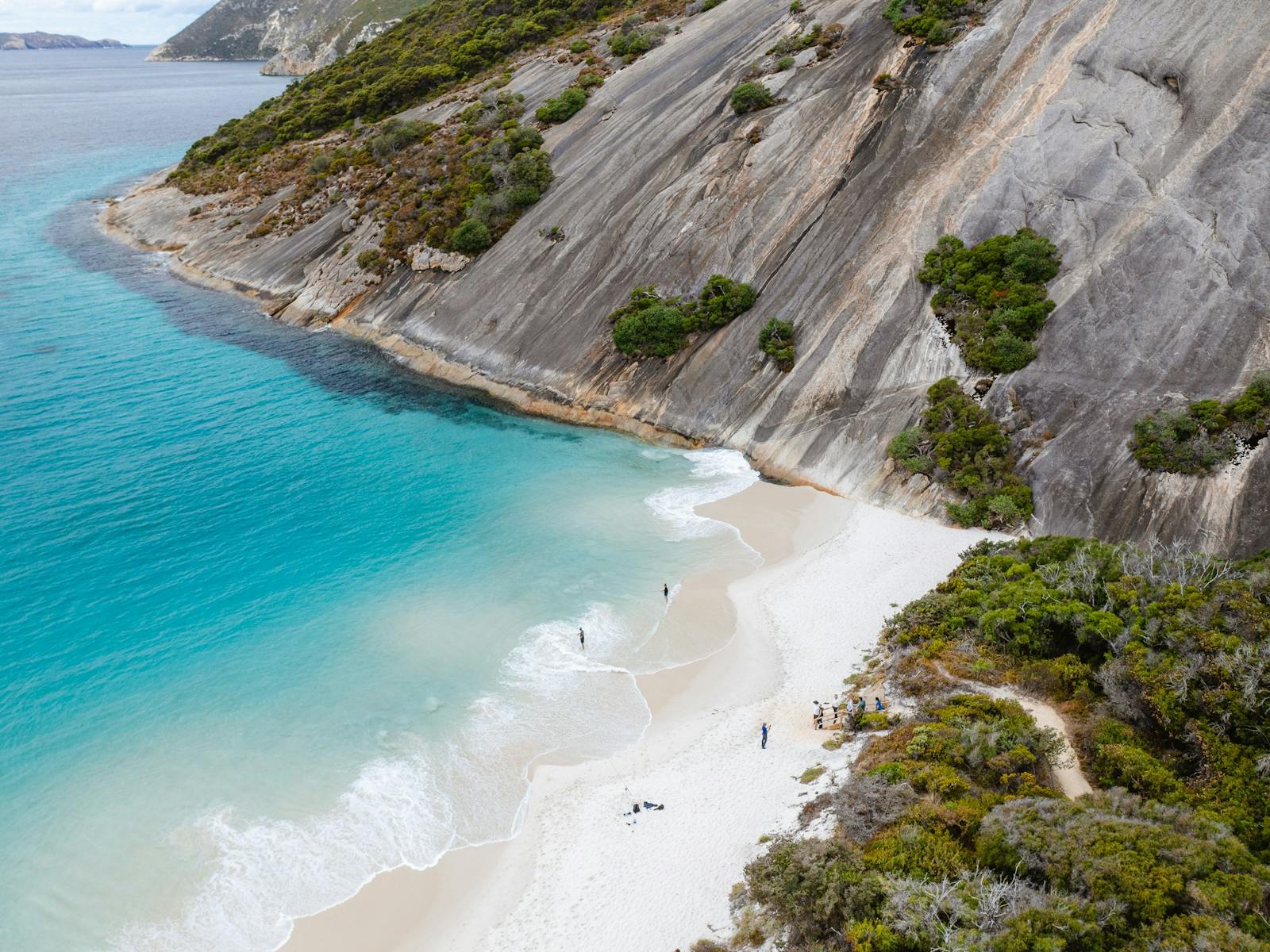 view along sheet granite headland with bright blue beach to left