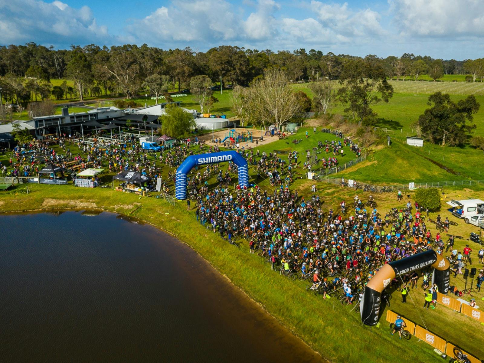 Drone aerial photo of mass group of riders ahead of race start, next to lake at CBCo. Brewery