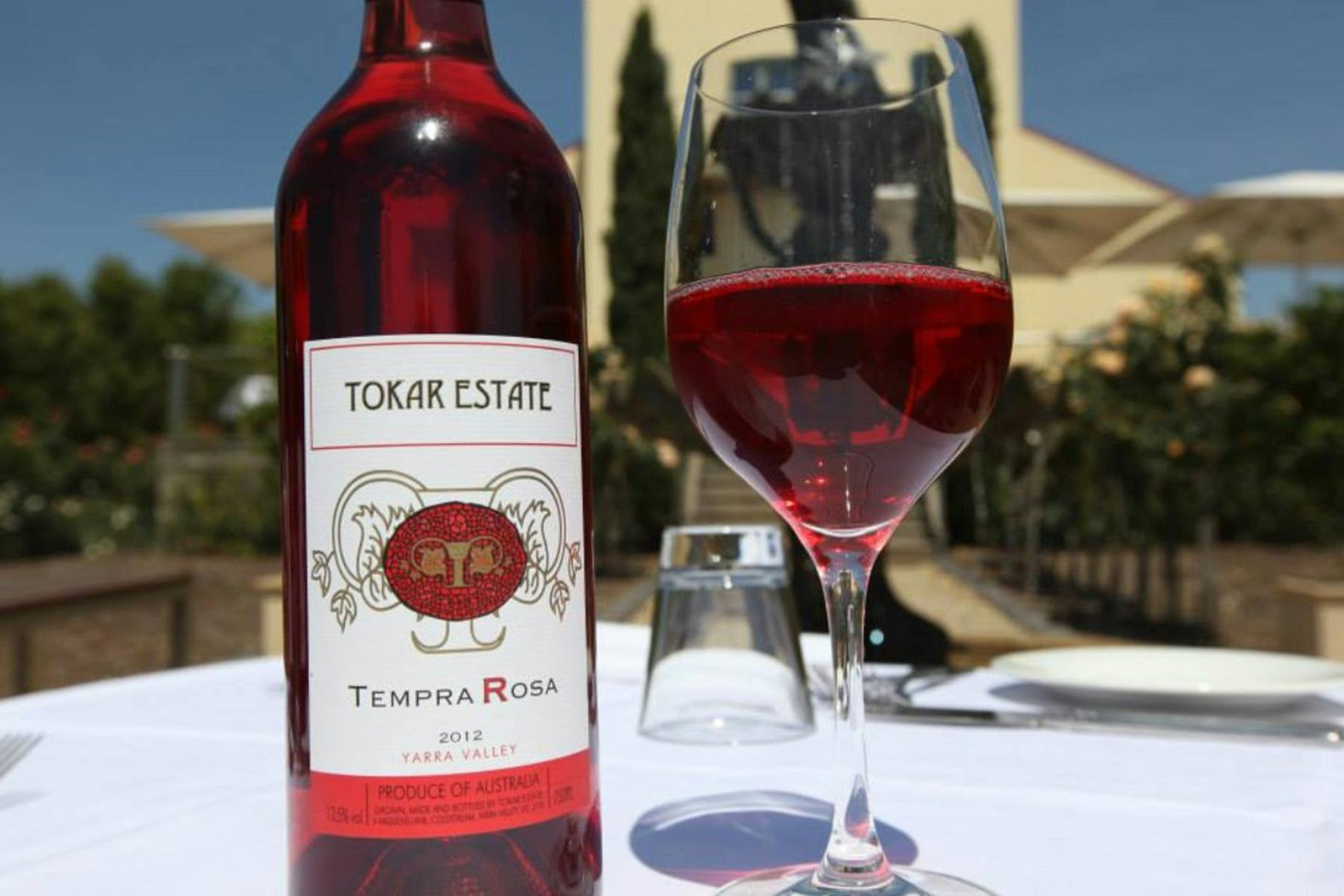 Bottle and glass of Tokar Estate Rose close up in front of Winery building