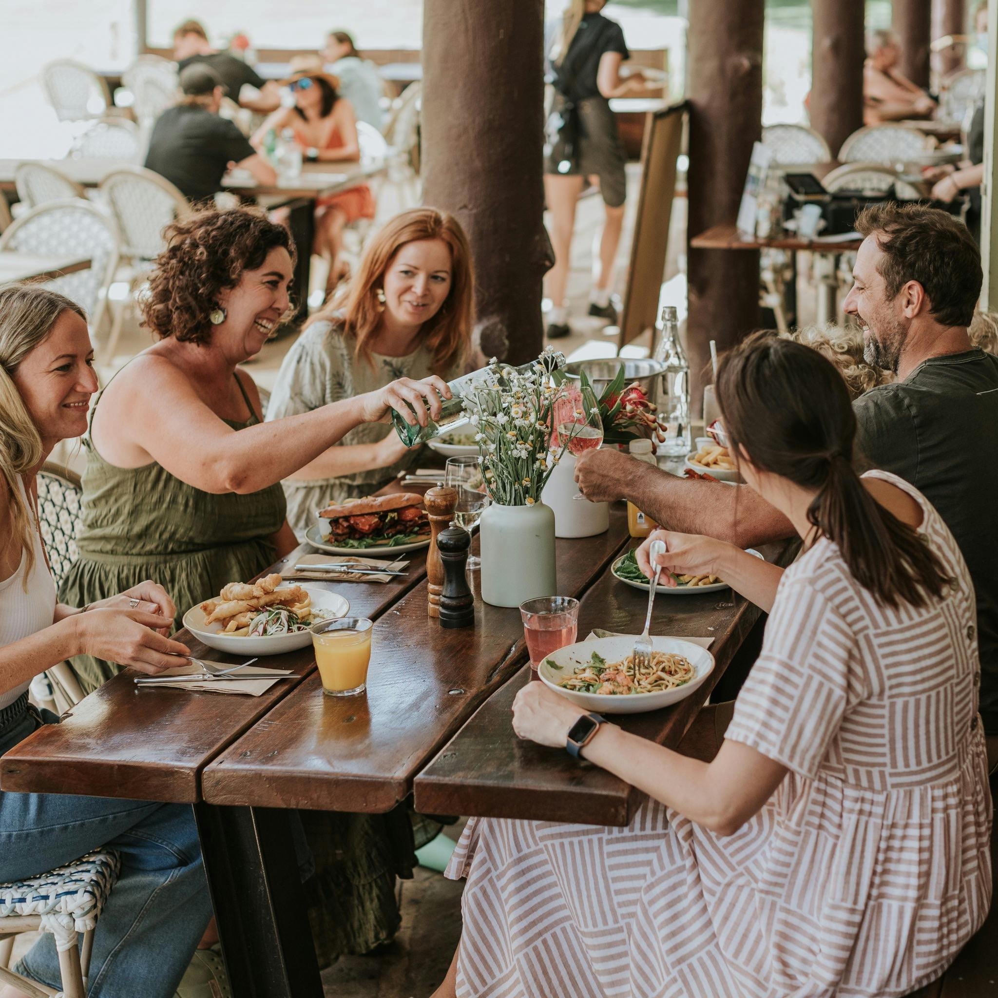 Group of 5 friends sharing meal and laughing at Audley Cafe