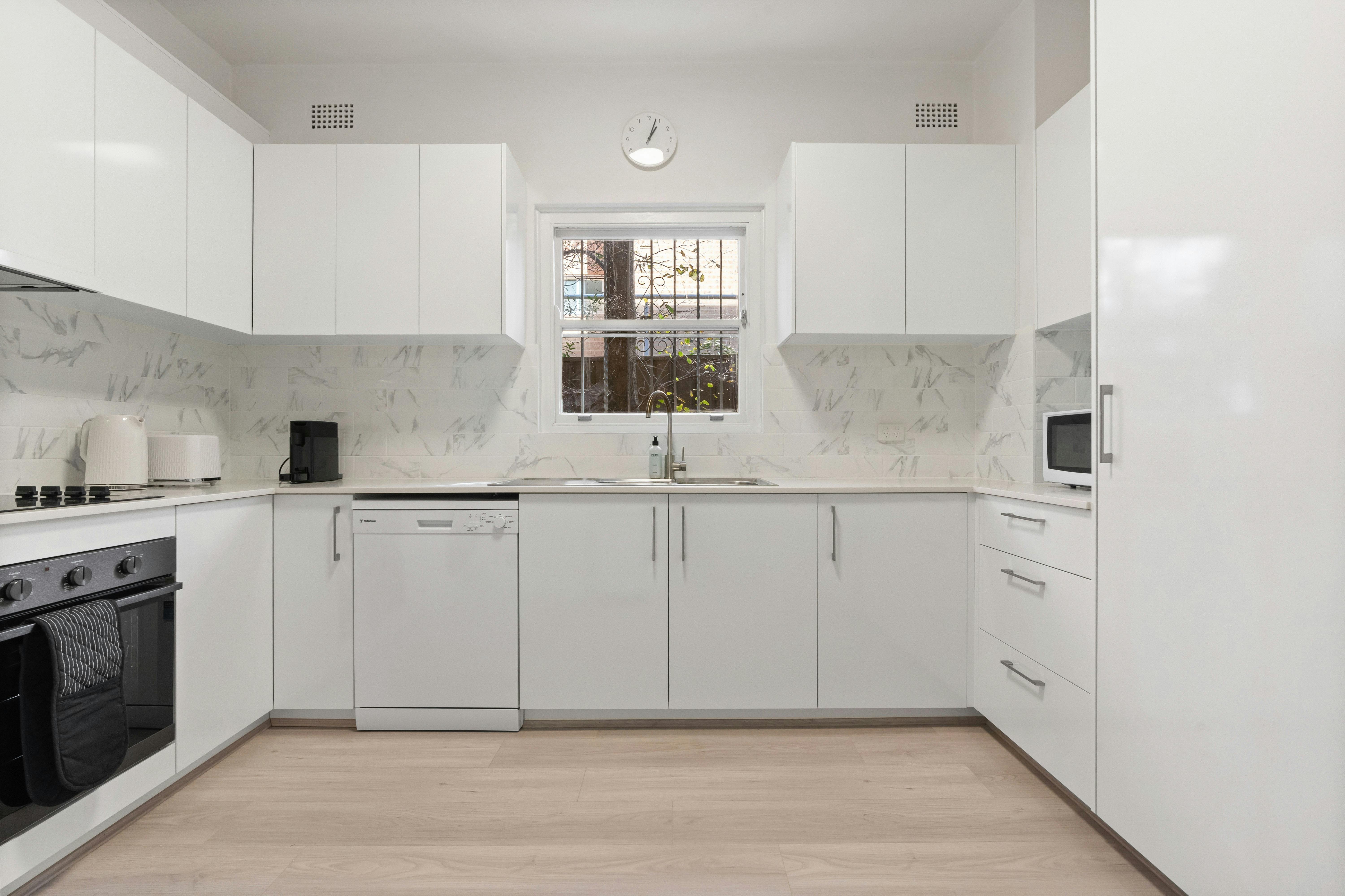 乾淨時尚的廚房配有白色櫥櫃和現代電器。