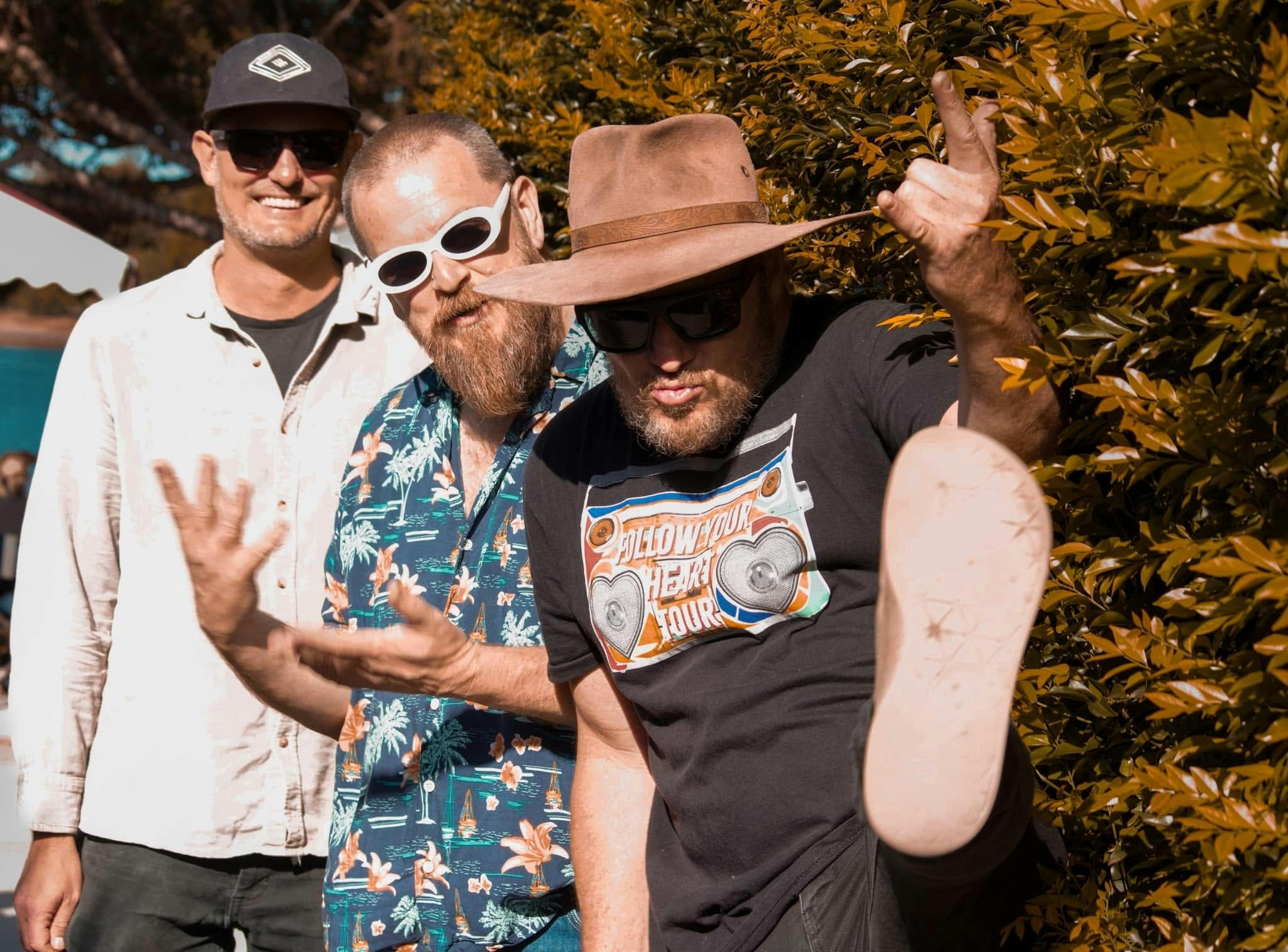 the men, one with white sunnies, one smiling and one kicking foot out