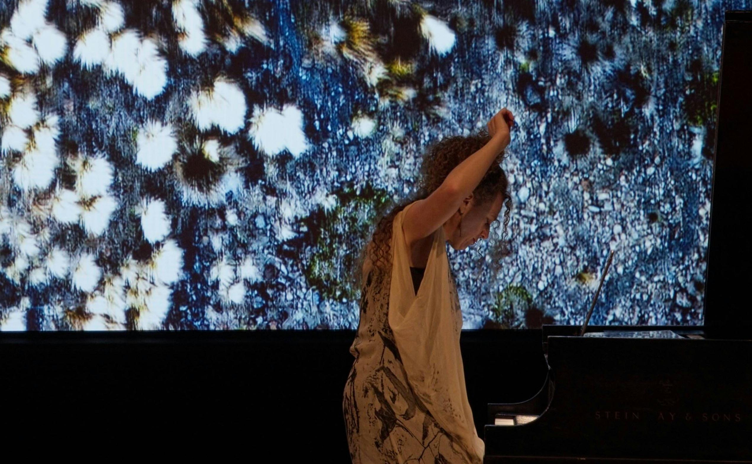 woman playing piano with abstract screen image behind