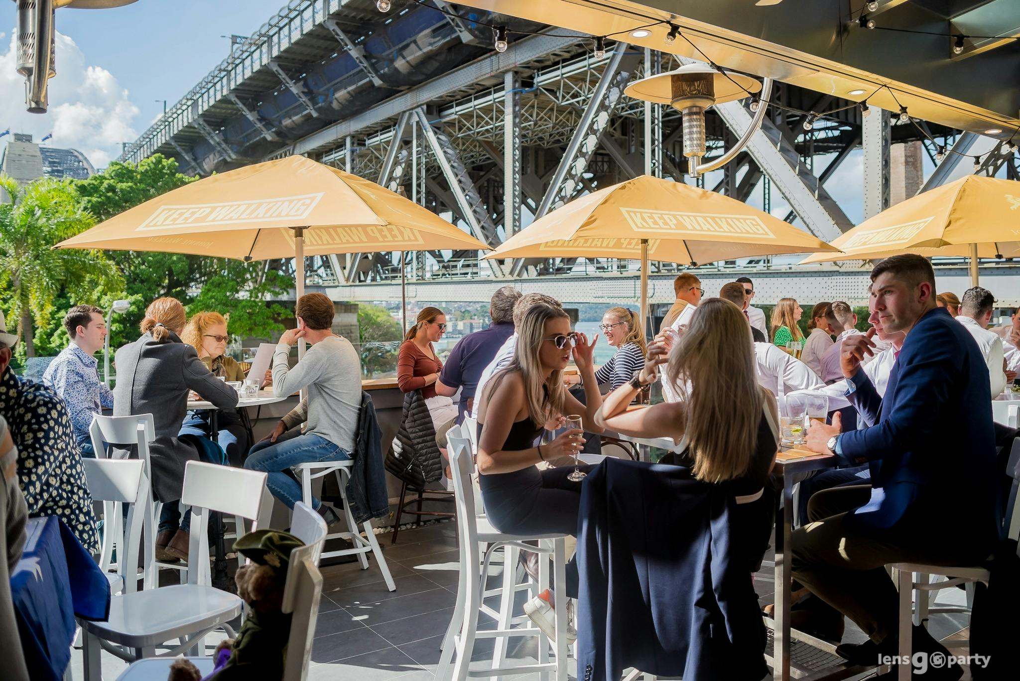 Patrons enjoying the rooftop terrace in the sun under yellow umbrellas