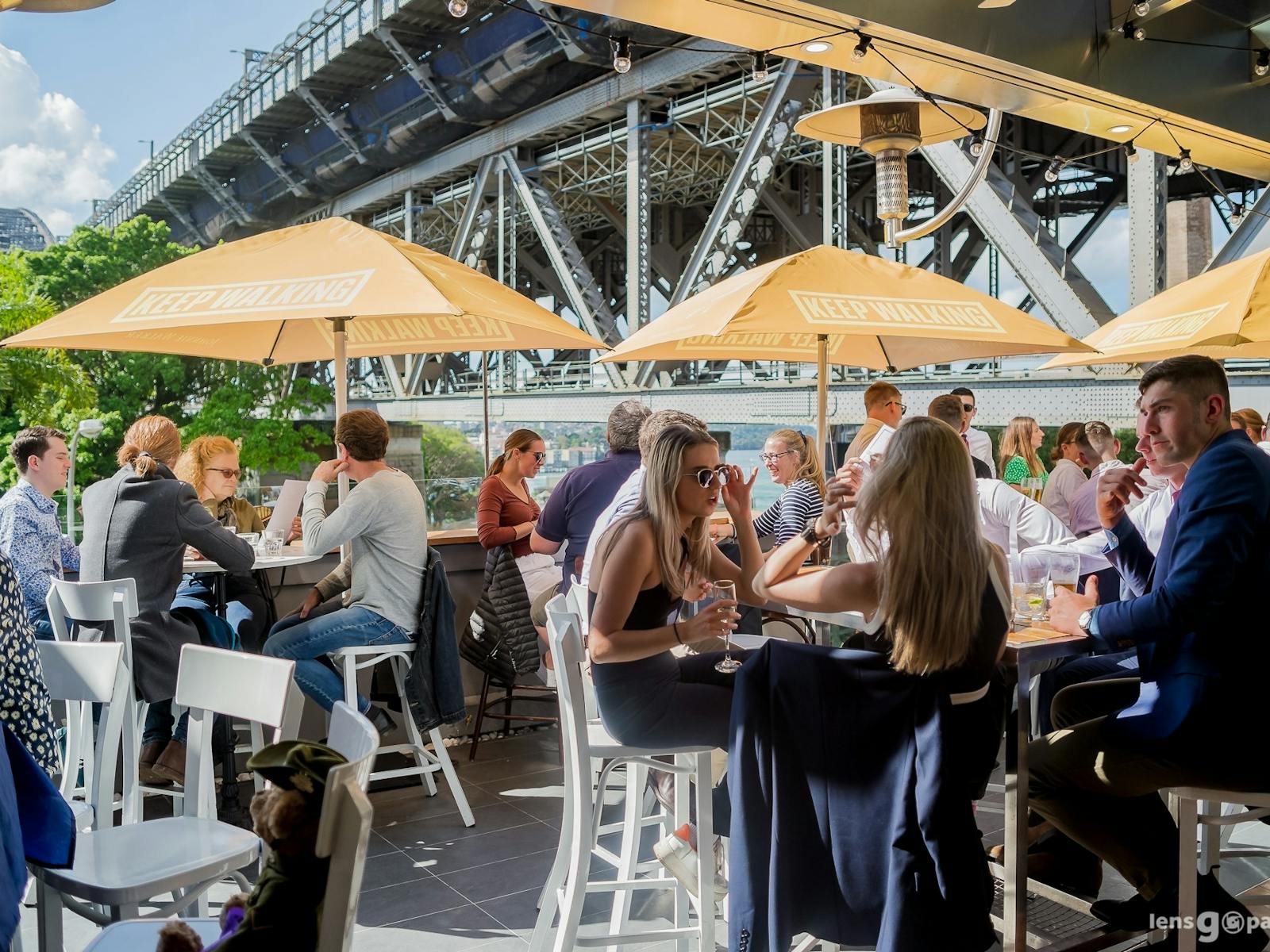 Patrons enjoying the rooftop terrace in the sun under yellow umbrellas