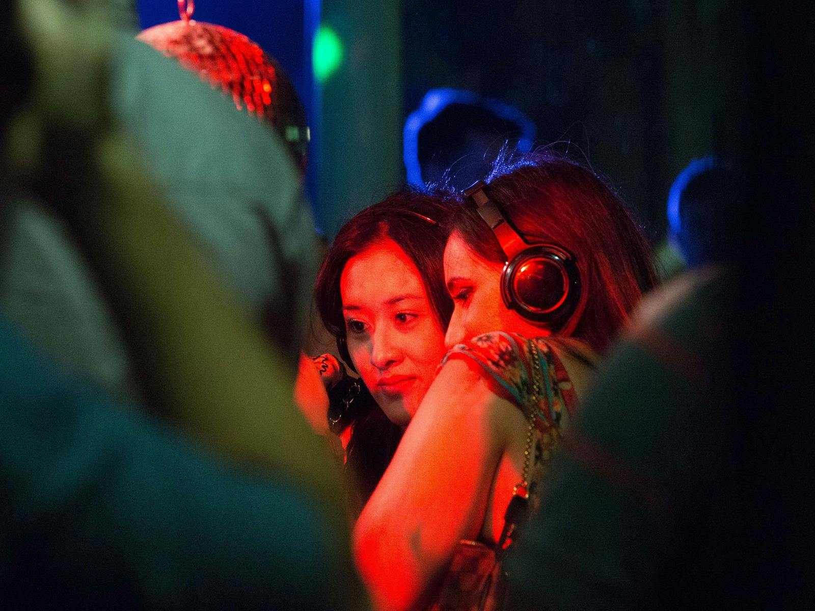 Two women listening to music with headphones at a party