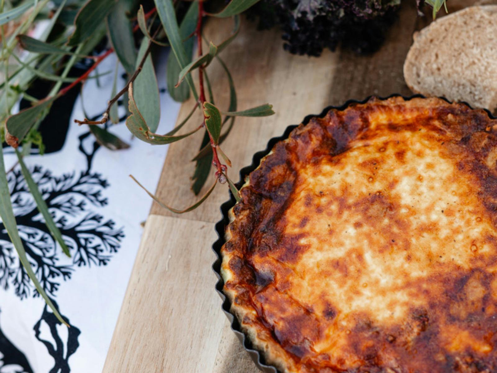 Freshly baked golden vegetable quiche displayed on a wooden table