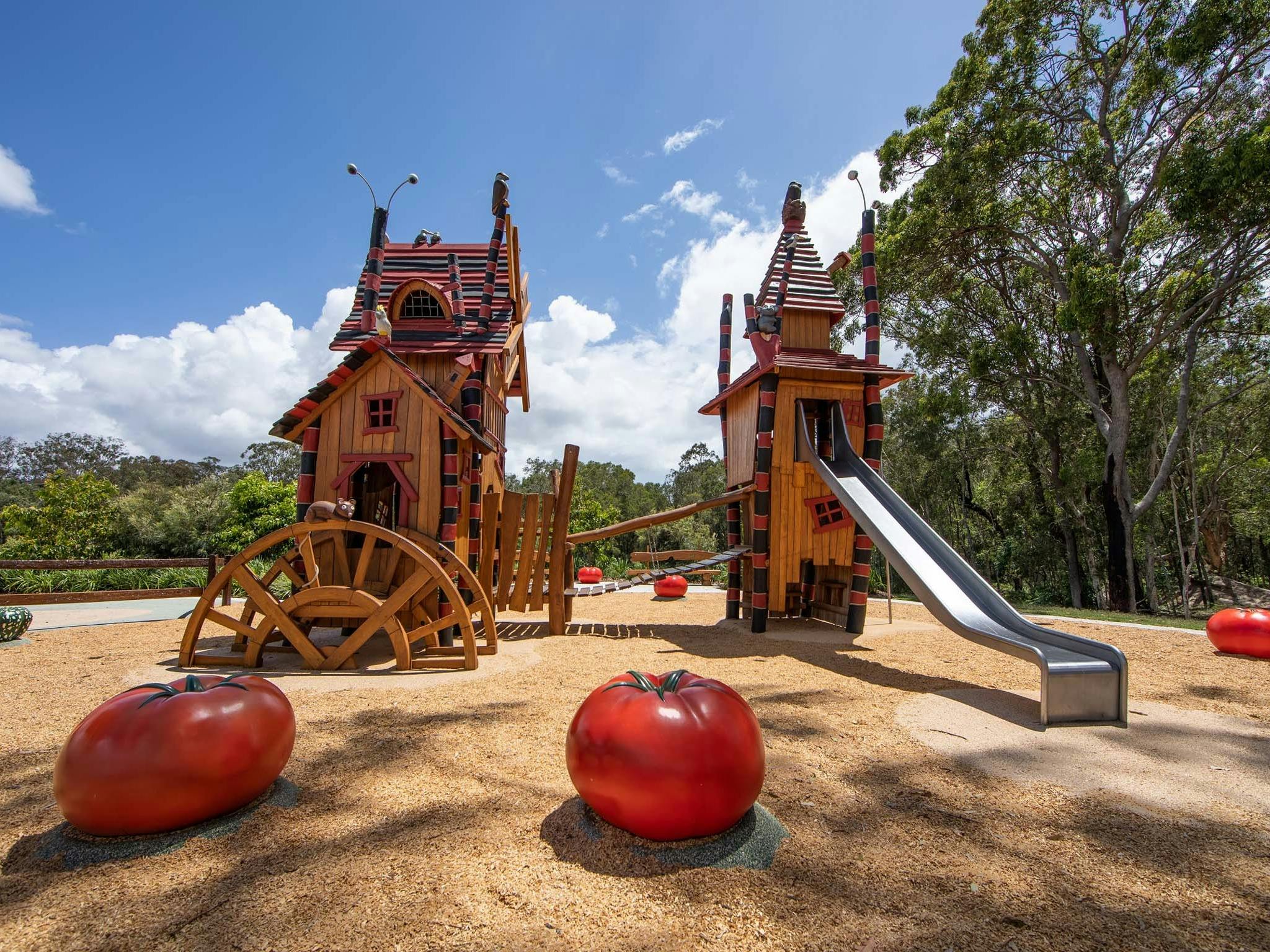 Two Halloween themed playground towers with a metal slide and two over sized tomatoes in foreground Two Halloween themed playground towers with a metal slide and two over sized tomatoes in foreground