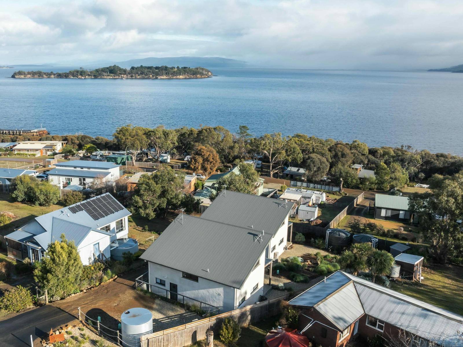 A aerial view of two identical units with sloping roofs overlooking the ocean.