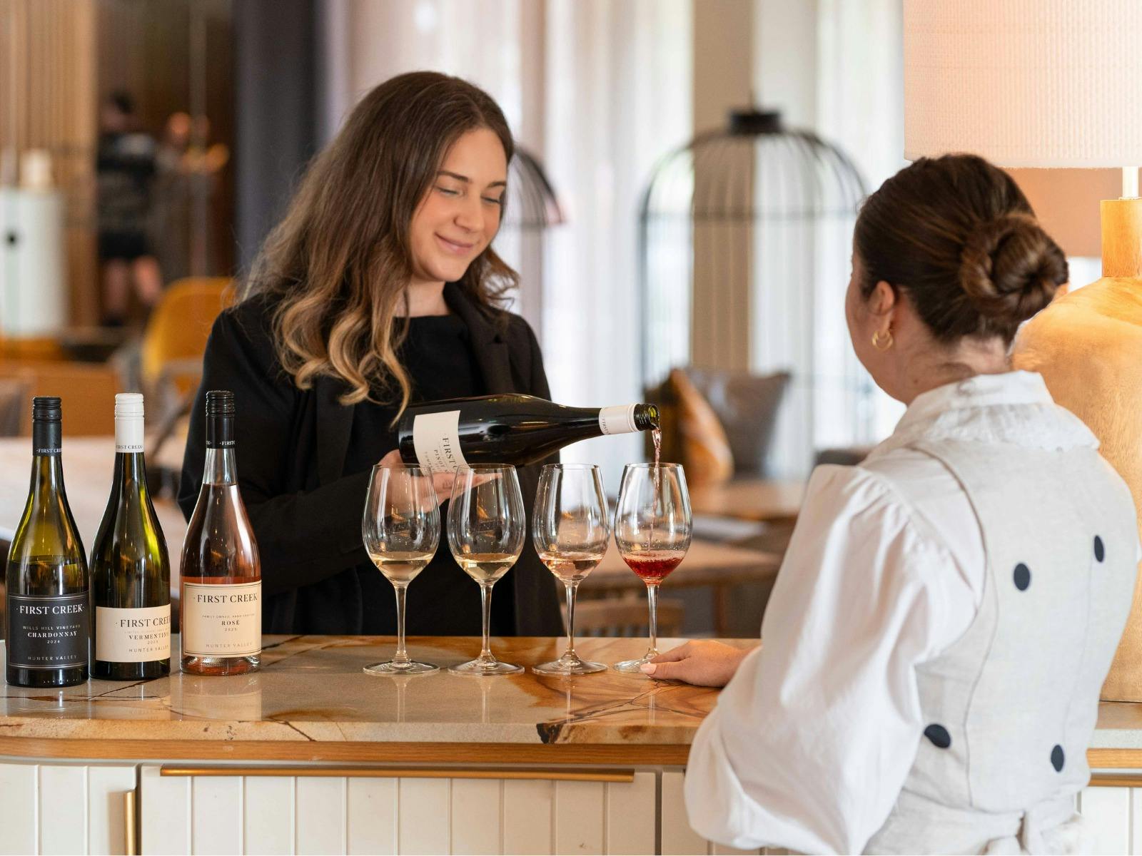 Cellar door wine tasting, woman pouring wine into glasses
