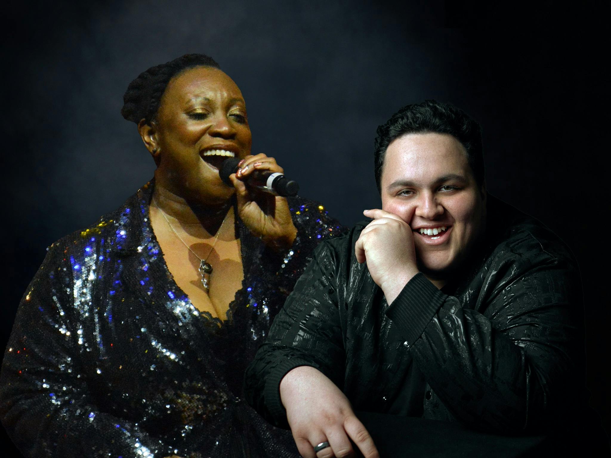 A woman singing with a man sitting smiling to camera