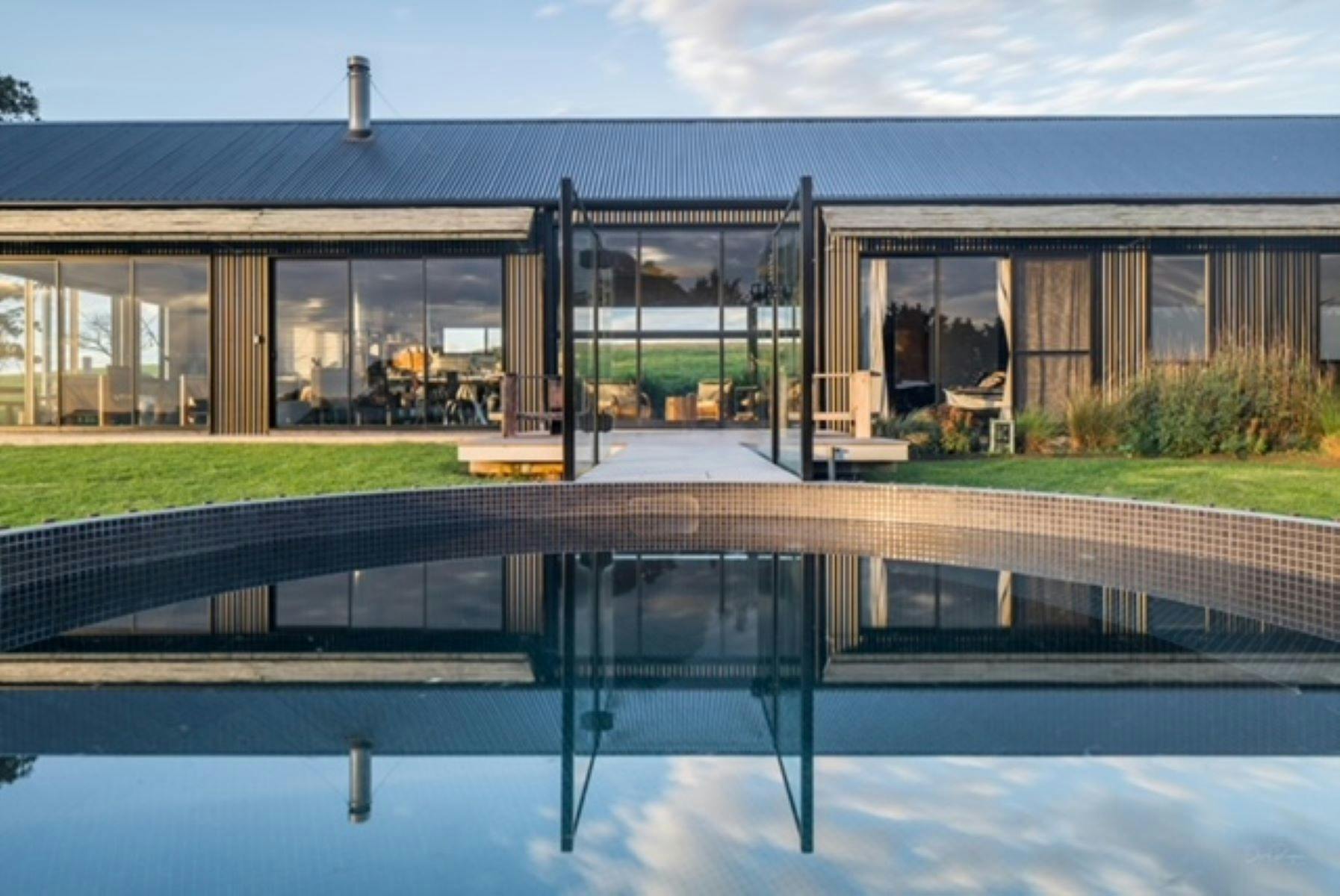 Image of front of home. Pool takes up the front of image with crystal clear blue water.