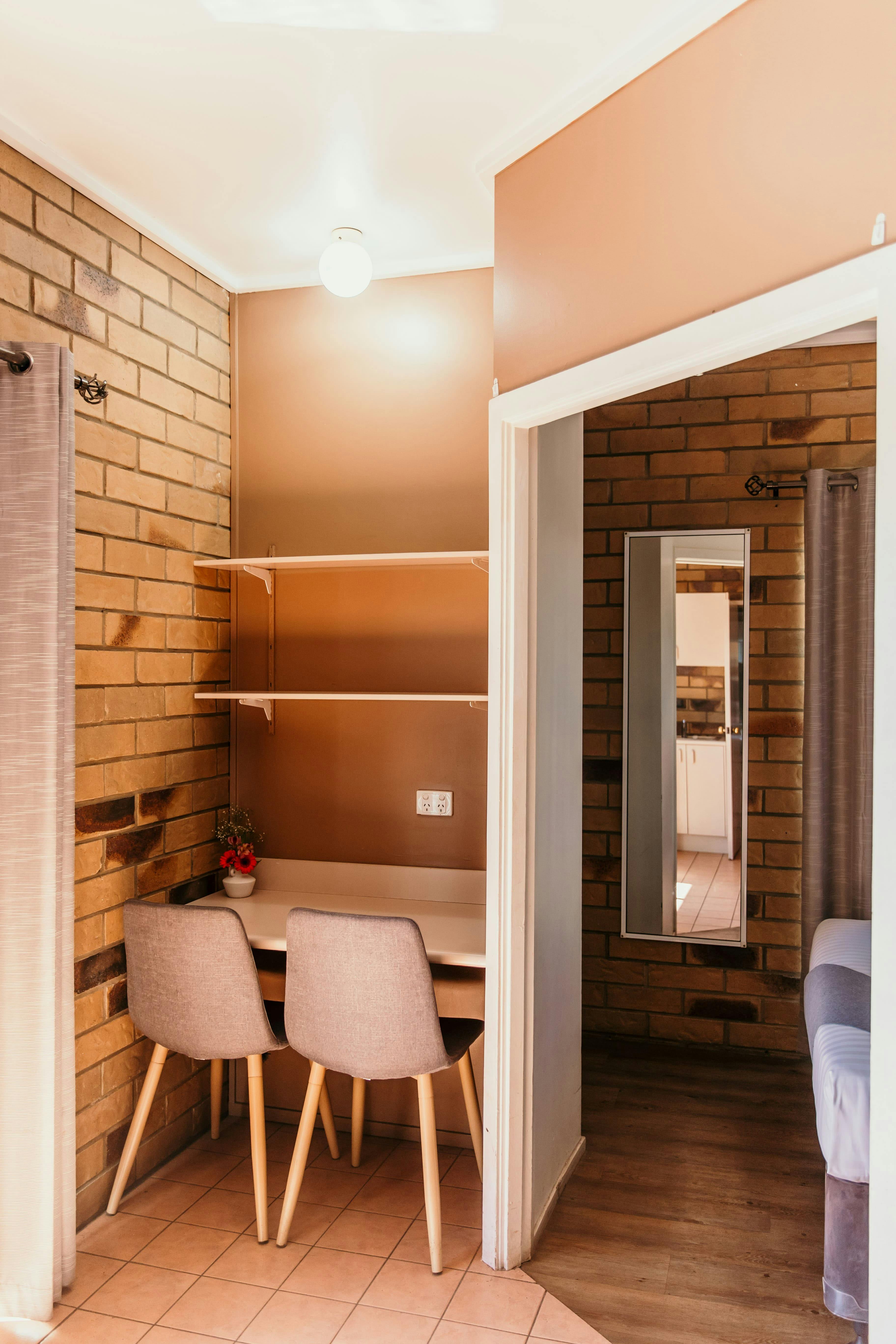 A small open corner study with shelves, a desk and 2 chairs.