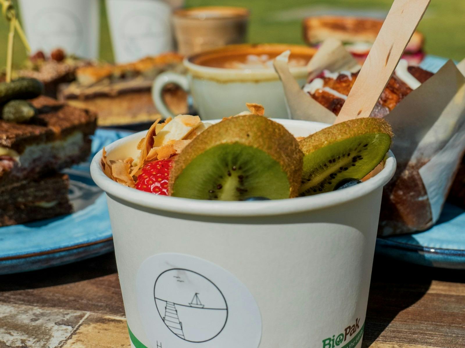 Zoomed in image of fruit salad in a cup on a table with other dishes behind