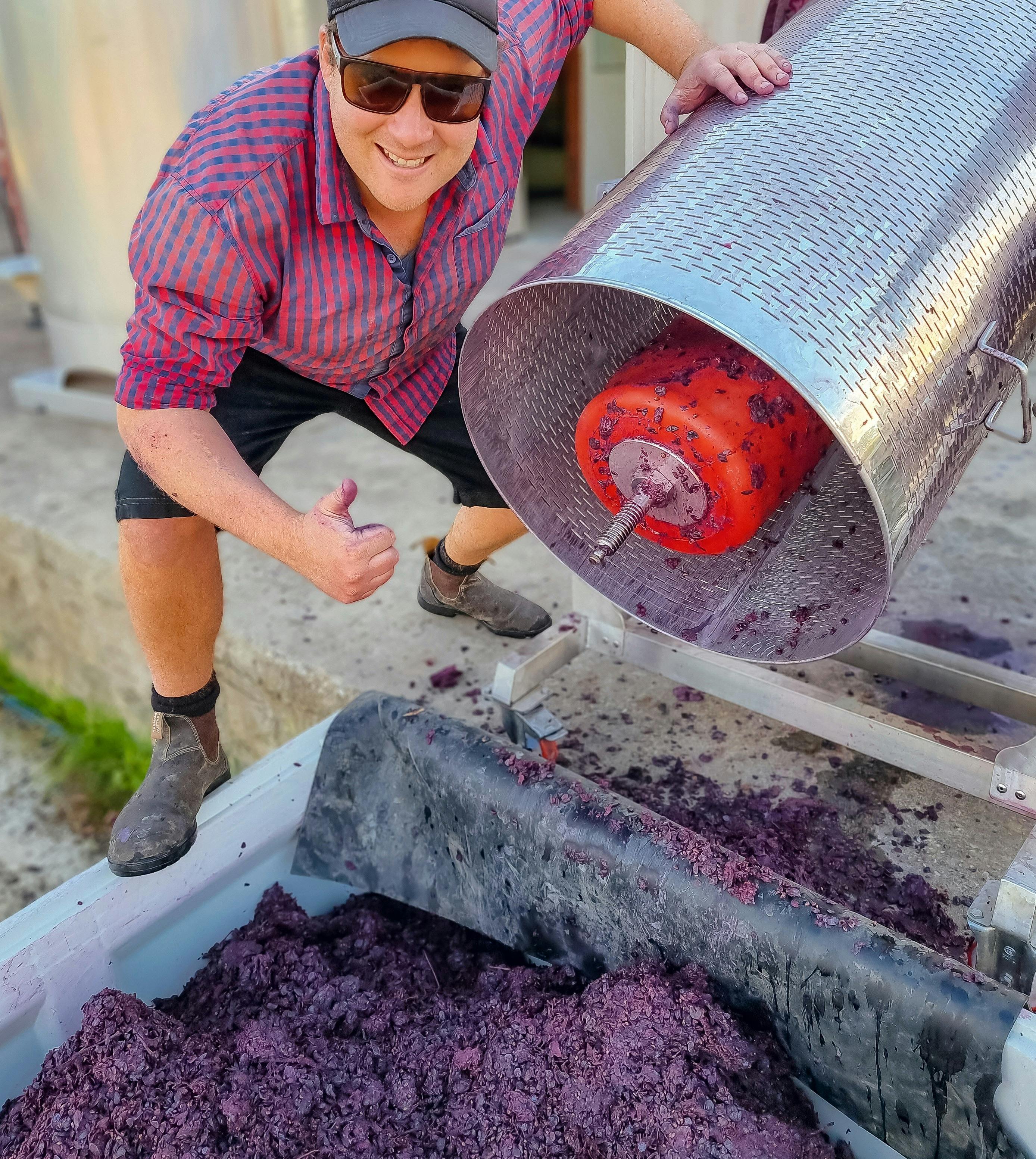 Scott tipping out pressed wine skins and giving a thumbs up