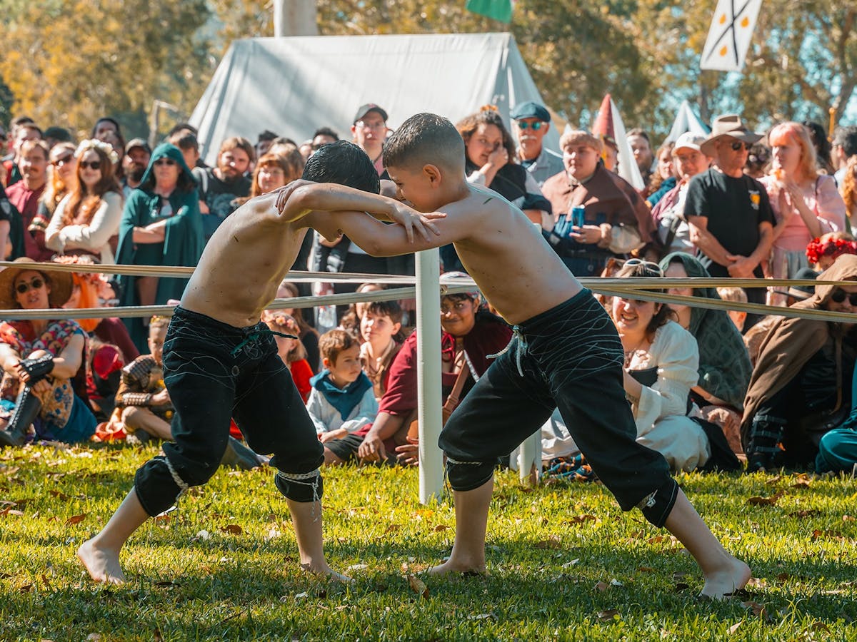 Two young turkish oil wrestlers demonstrating the sport to a crowd