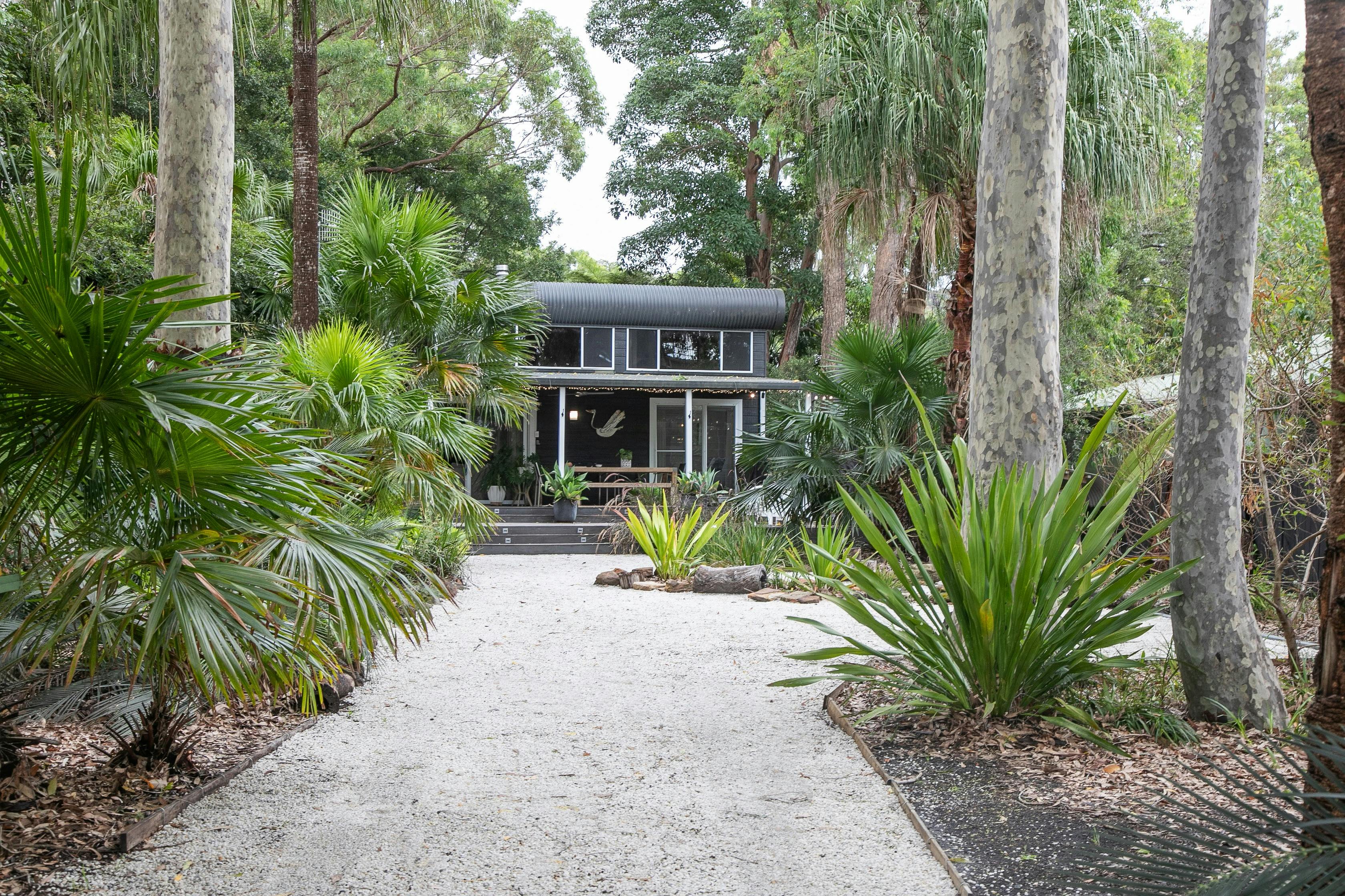 House facade, white gravel driveway, lush gardens