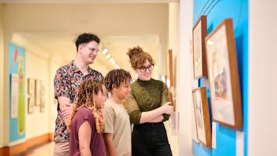 Two children and two adults standing together looking at a picture on the wall