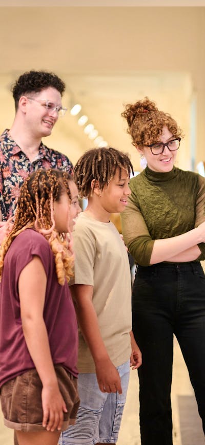 Two children and two adults standing together looking at a picture on the wall