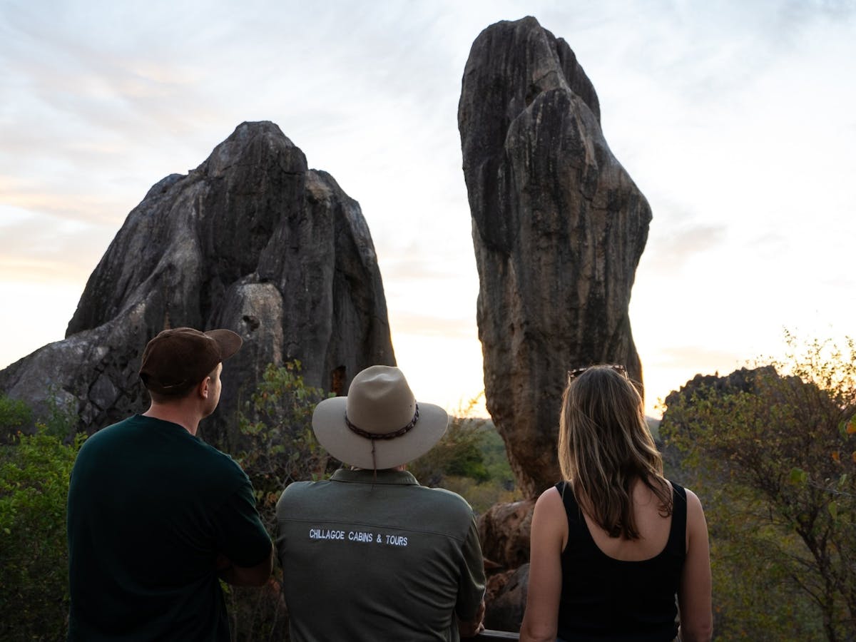 A tour guide, man and woman view balancing rock in chillagoe, tropical north qld.