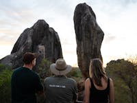 A tour guide, man and woman view balancing rock in chillagoe, tropical north qld.