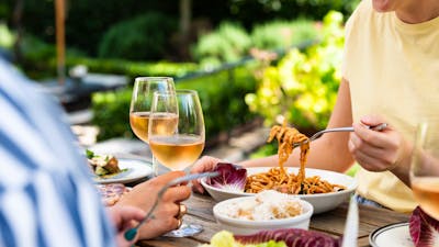 Table of food and wine set out before three guests.