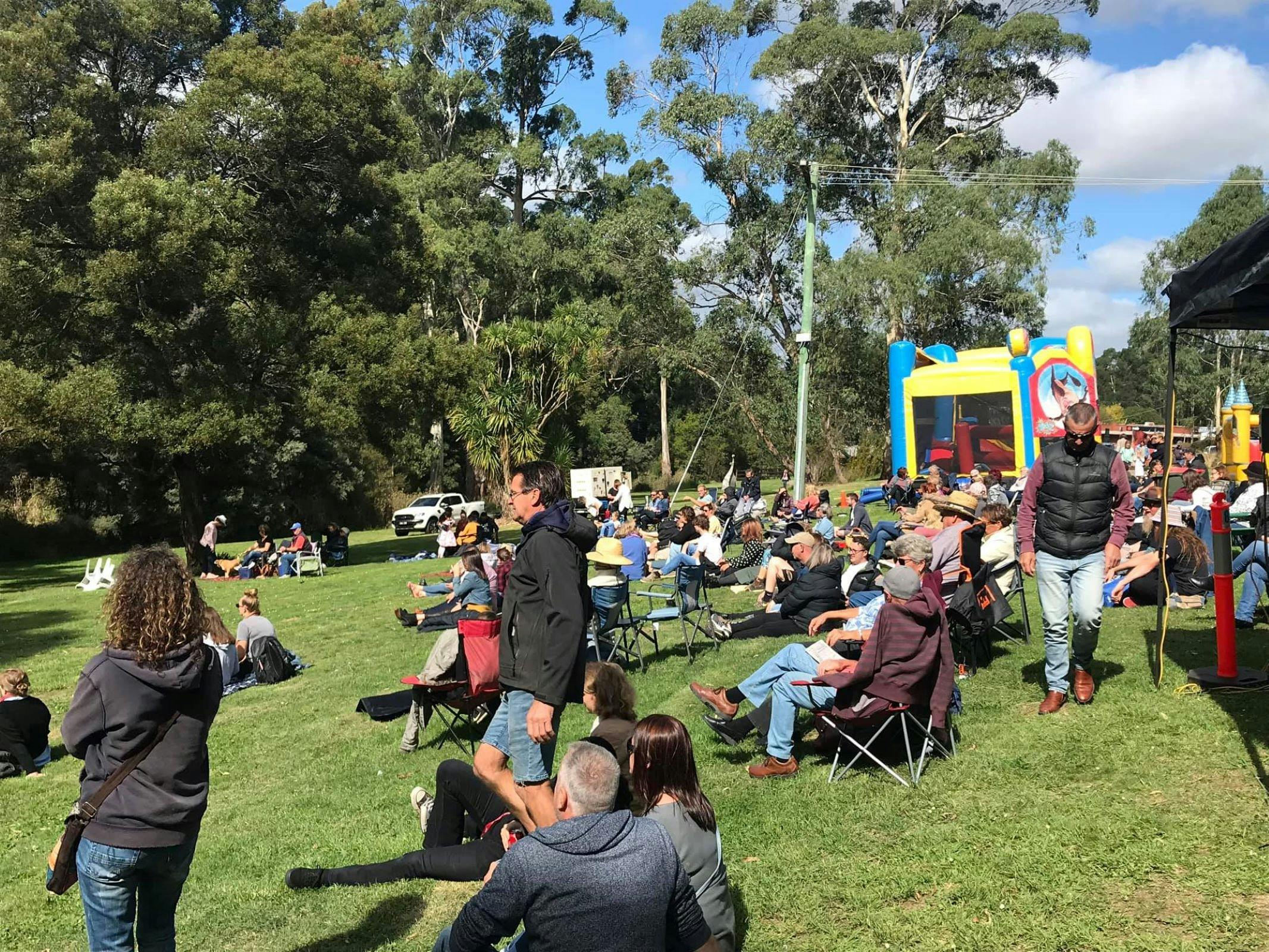 Spectators sitting on the grass watching performers on stang