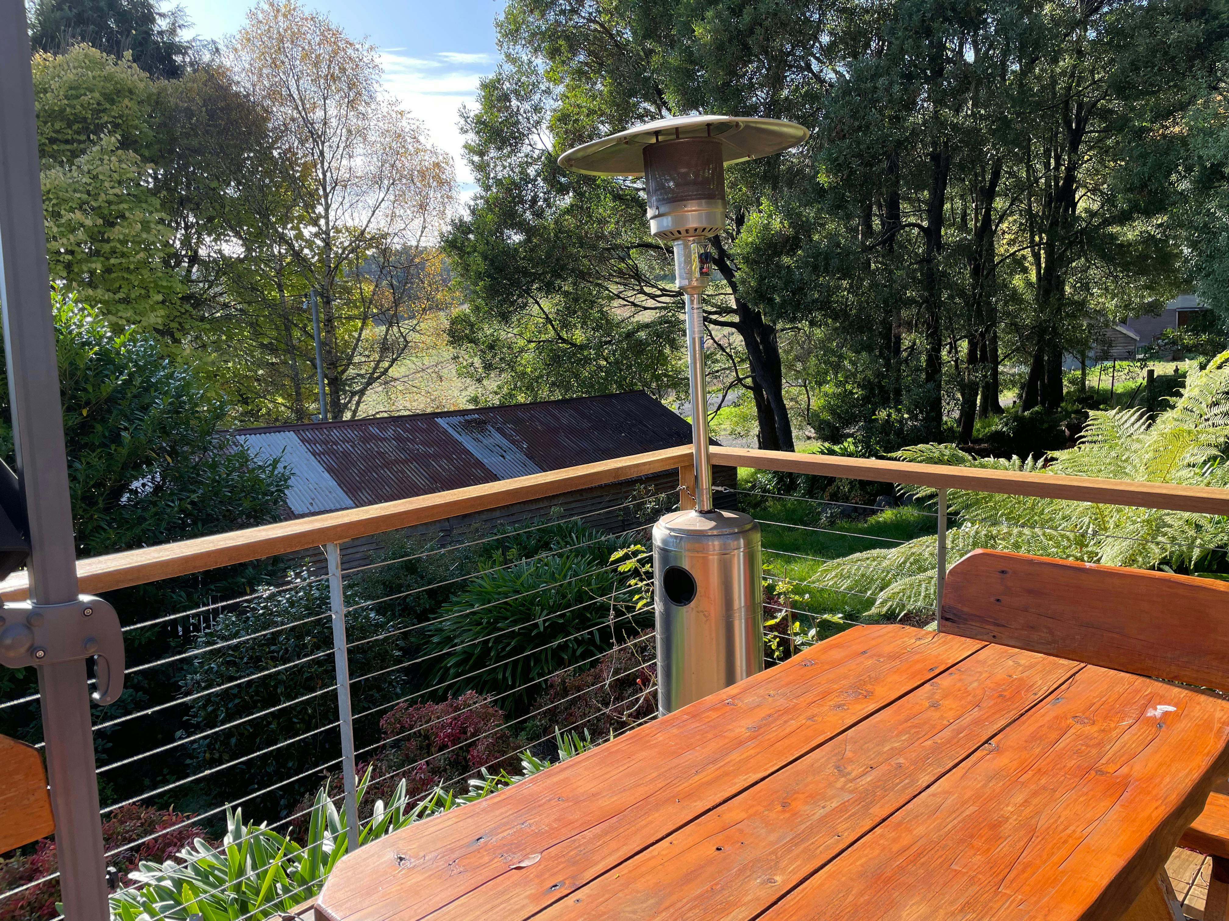 Wooden table on deck overlooking garden and rustic shed