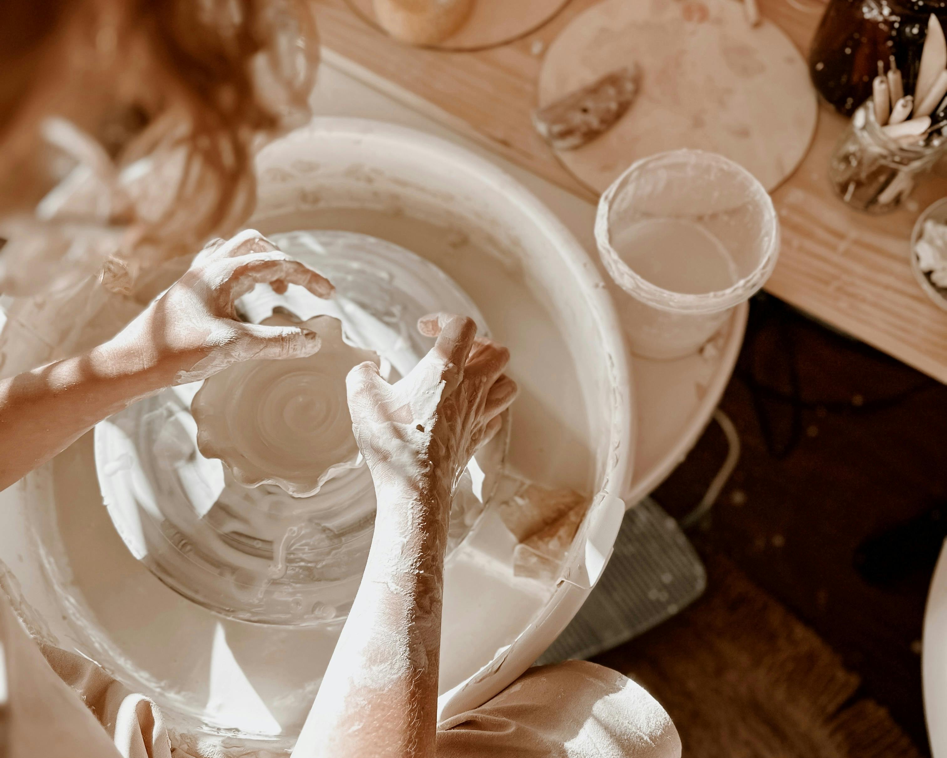 Woman making clay bowl on pottery wheel