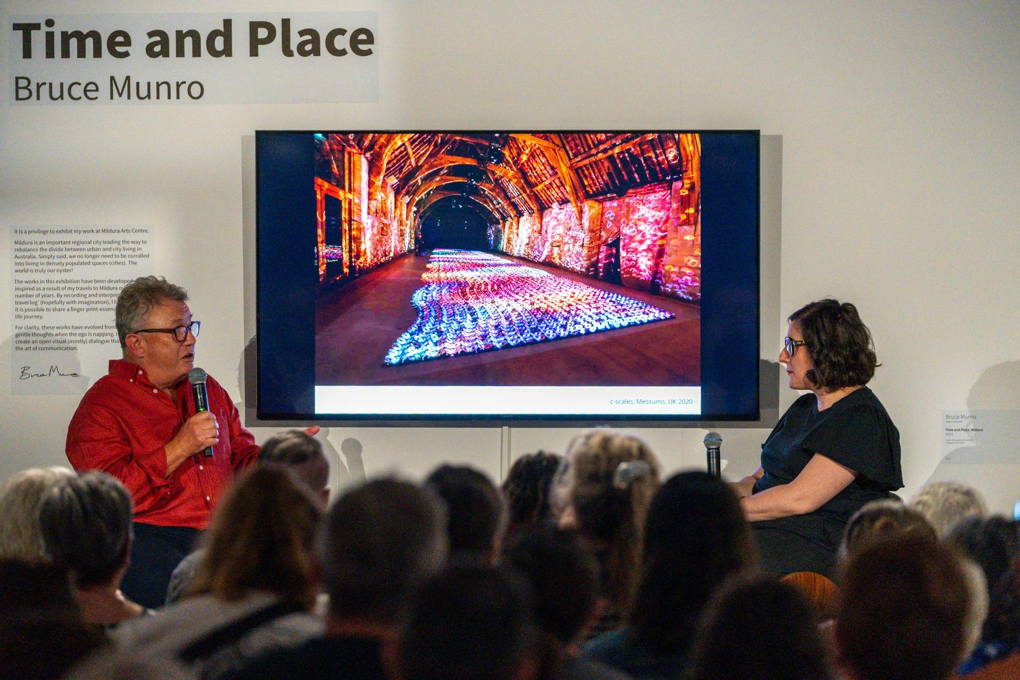 Two people on stage in front of a seated crowd of people