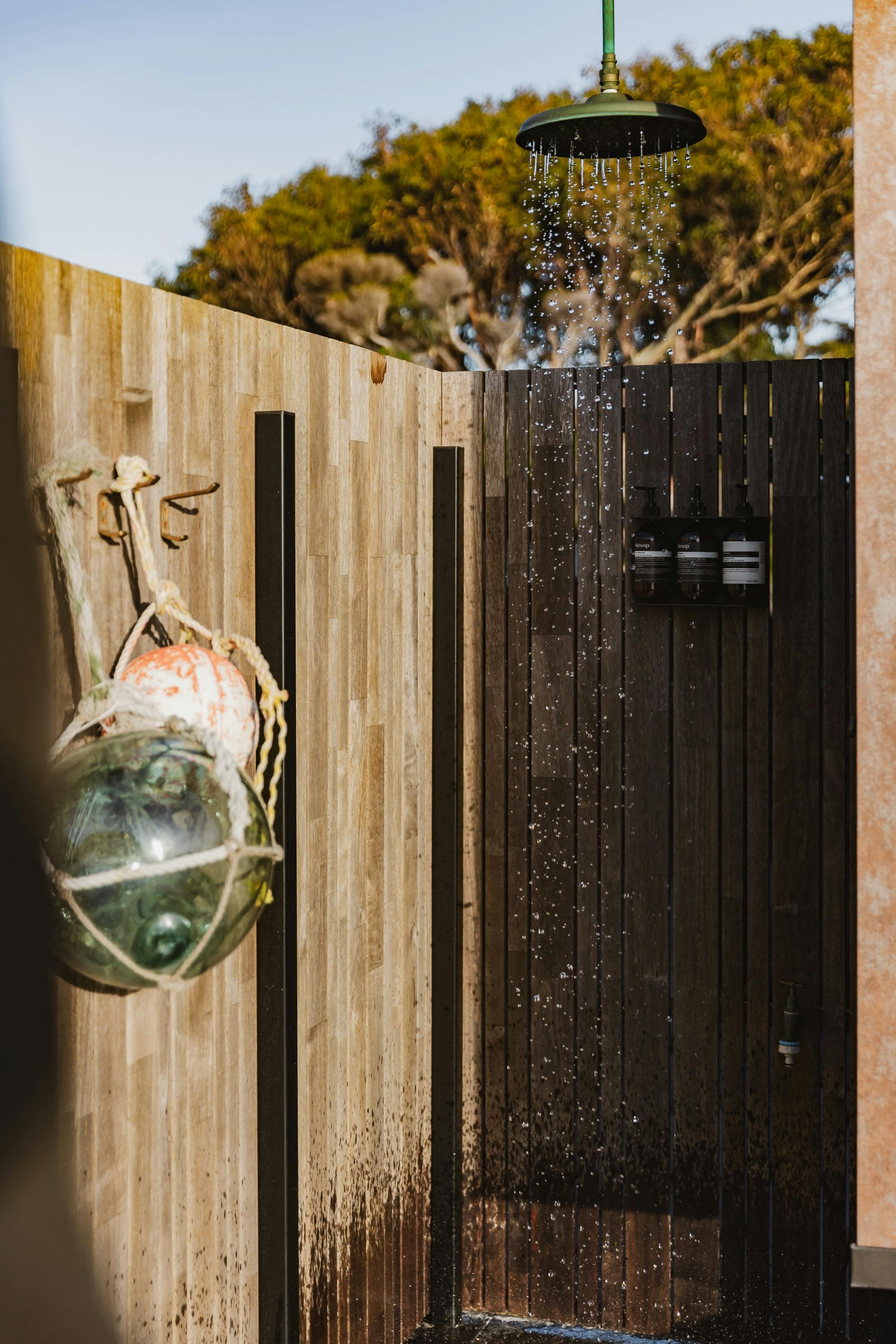 Timber outdoor shower with rainfall fittings and coastal décor details at Cooinda On The Beach.