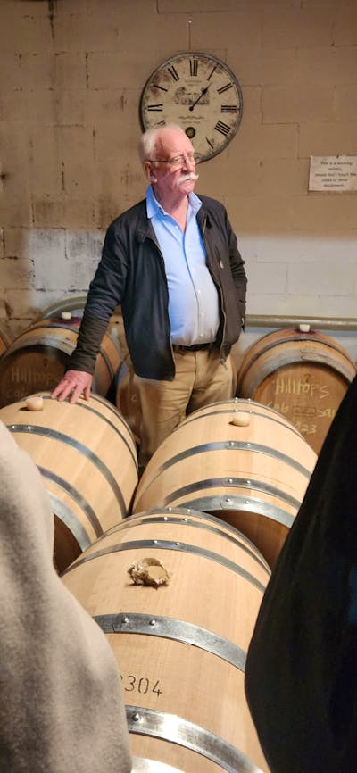 A man standing in front of a group of wooden barrels.