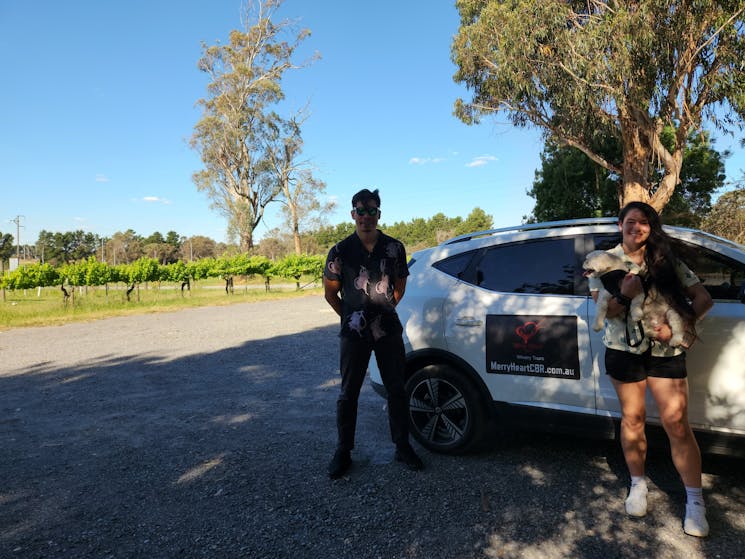 A couple pose with their pet dog on a winery tour in Murrumbateman