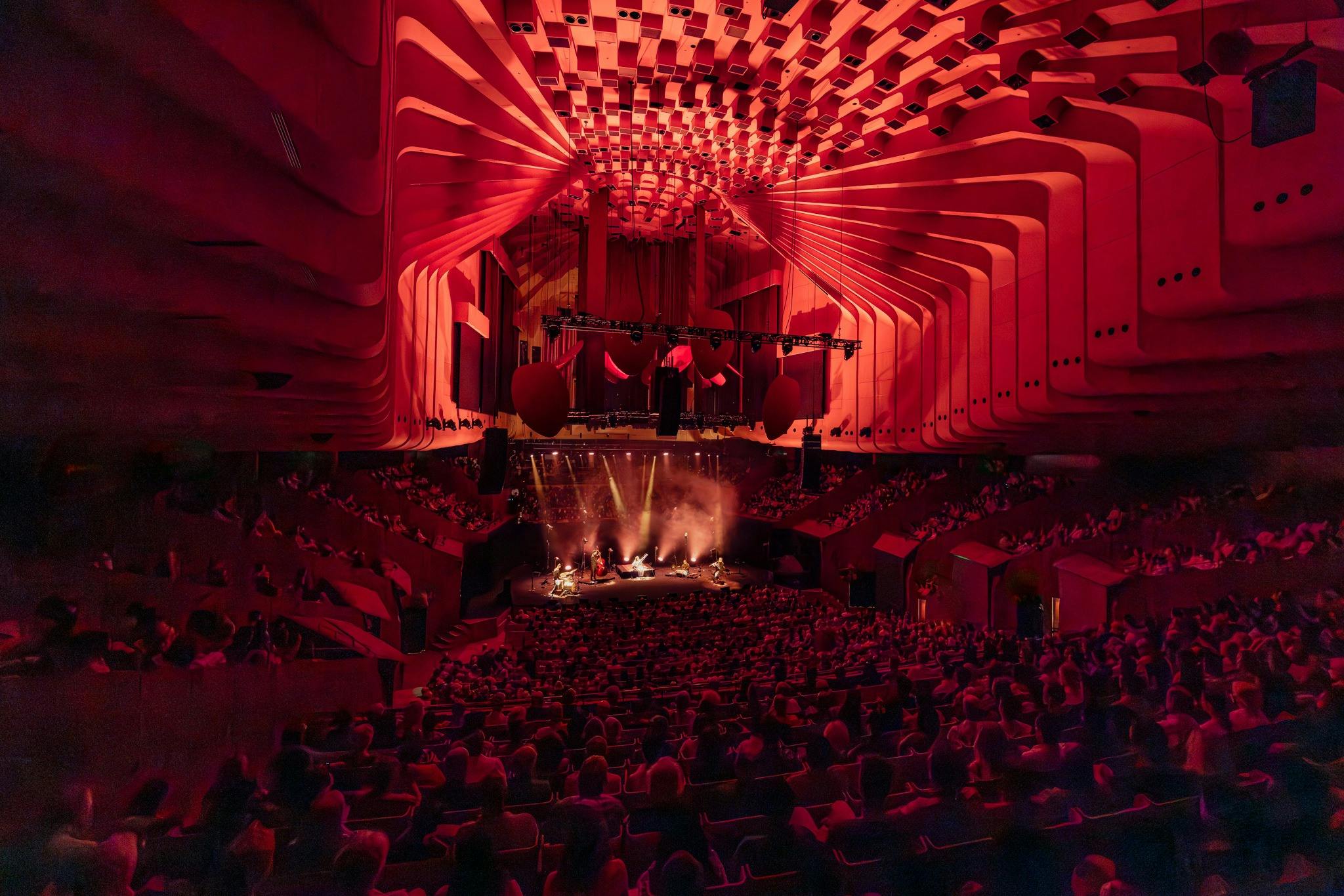 Interior of Sydney Opera House Concert Hall, full audience with dramatic red lighting